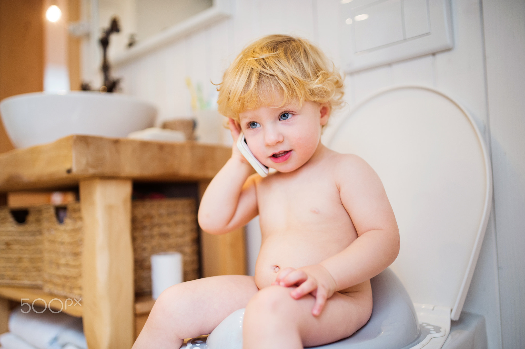Cute toddler boy with smartphone in the bathroom.