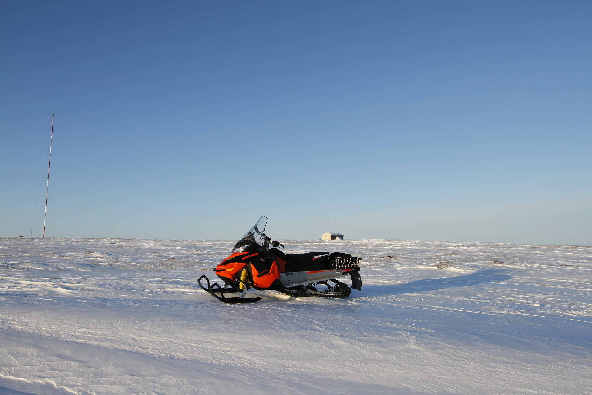 Canon EF-S 10-22mm F3.5-4.5 USM sample photo. A red snow machine on a white winter arctic landscape with snow on the ground a blue endless sky photography