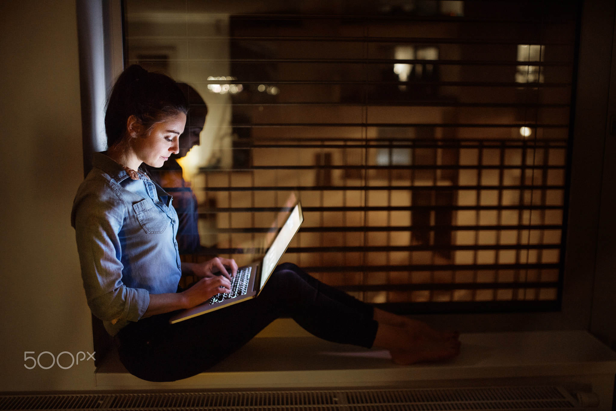 A woman working on a laptop at night.