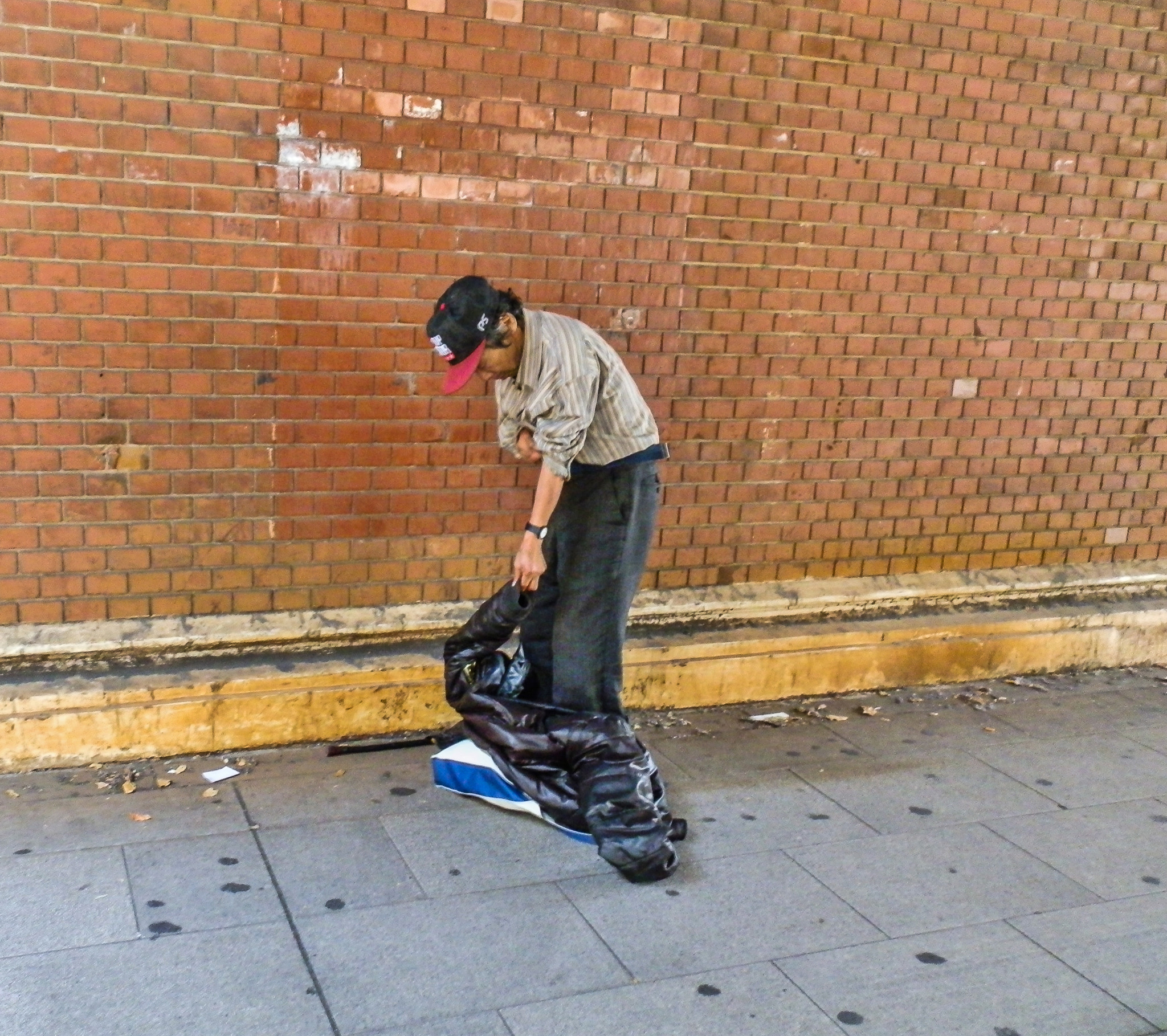 Olympus SZ-10 sample photo. A man who changes clothes in front of a brick wall photography