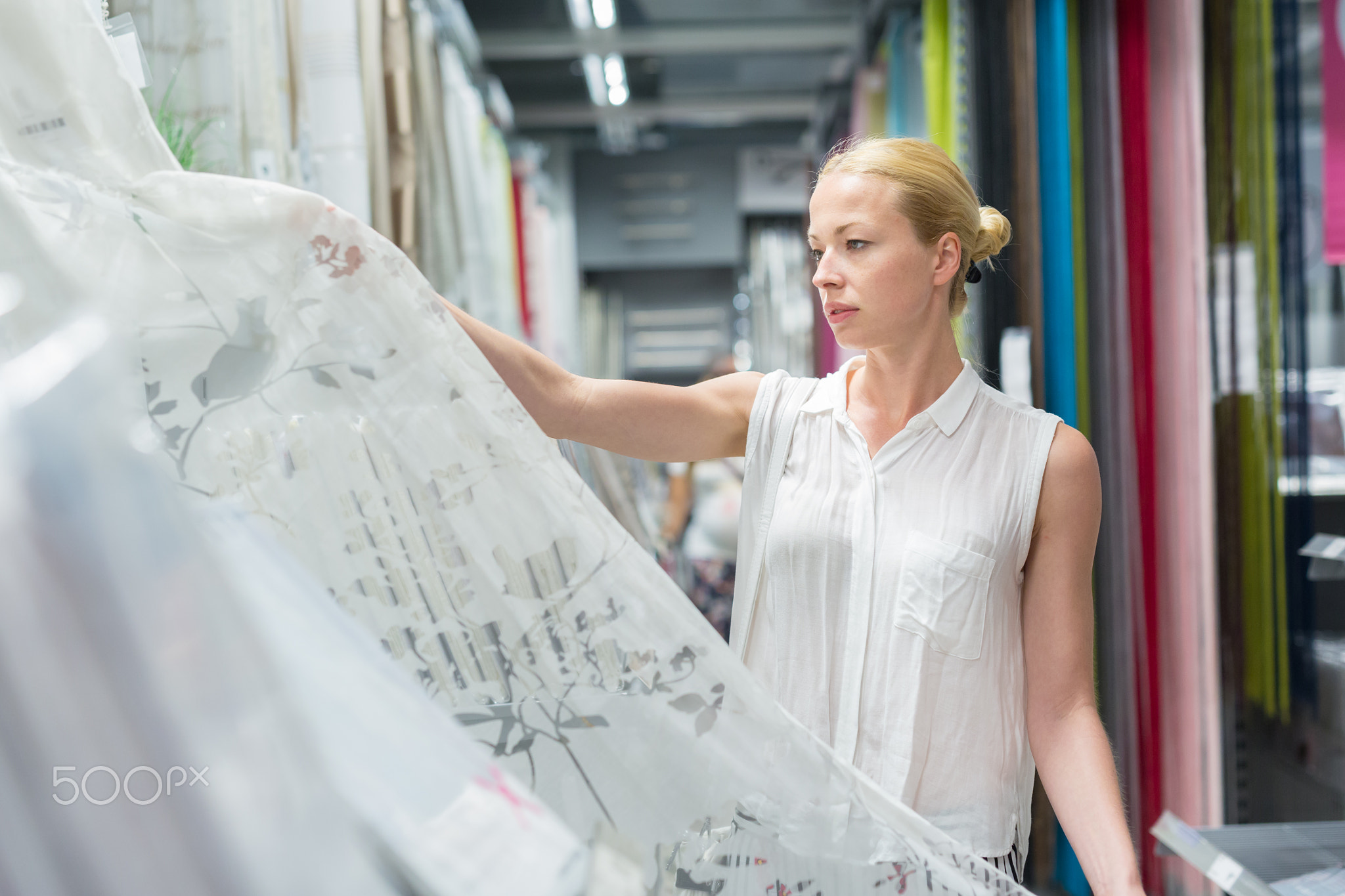 Beautiful housewife buying white curtains in home decor furnishings store.