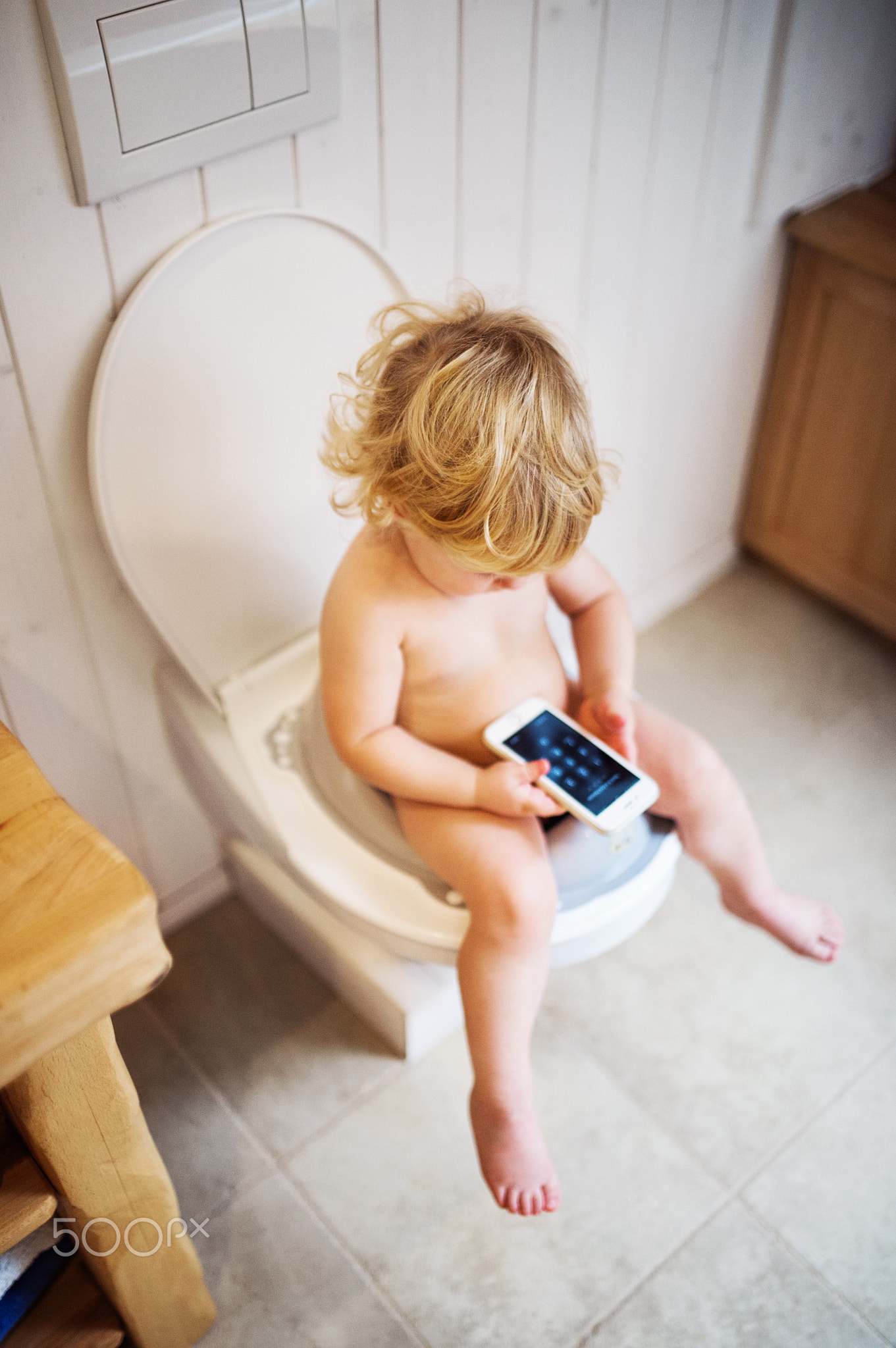 Cute toddler boy with smartphone in the bathroom.