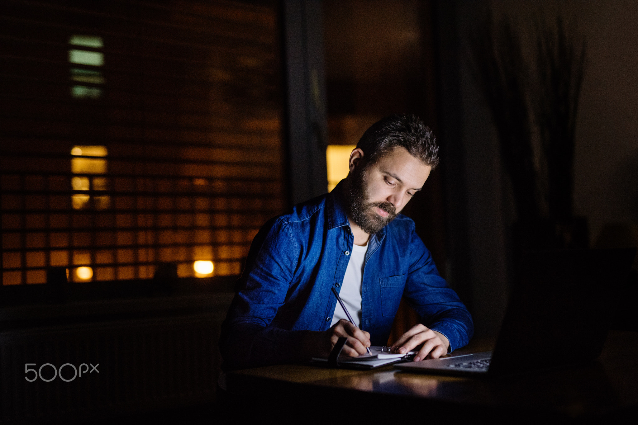 A man working on a laptop at home at night.