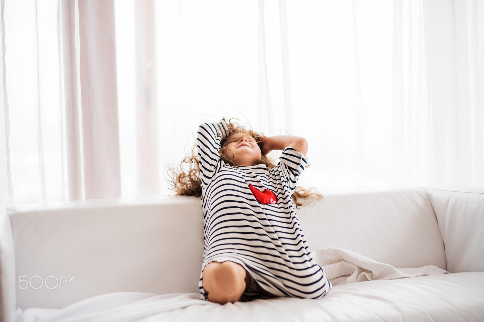 A small happy girl in striped T-shirt at home having fun.