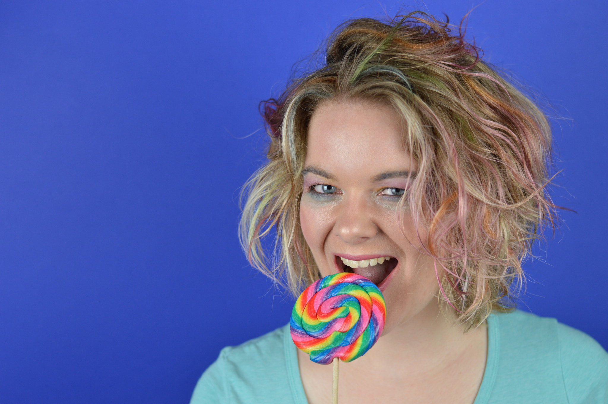 Nikon D3200 + Nikon AF-S Nikkor 50mm F1.8G sample photo. Blond woman biting into a big lollipop photography