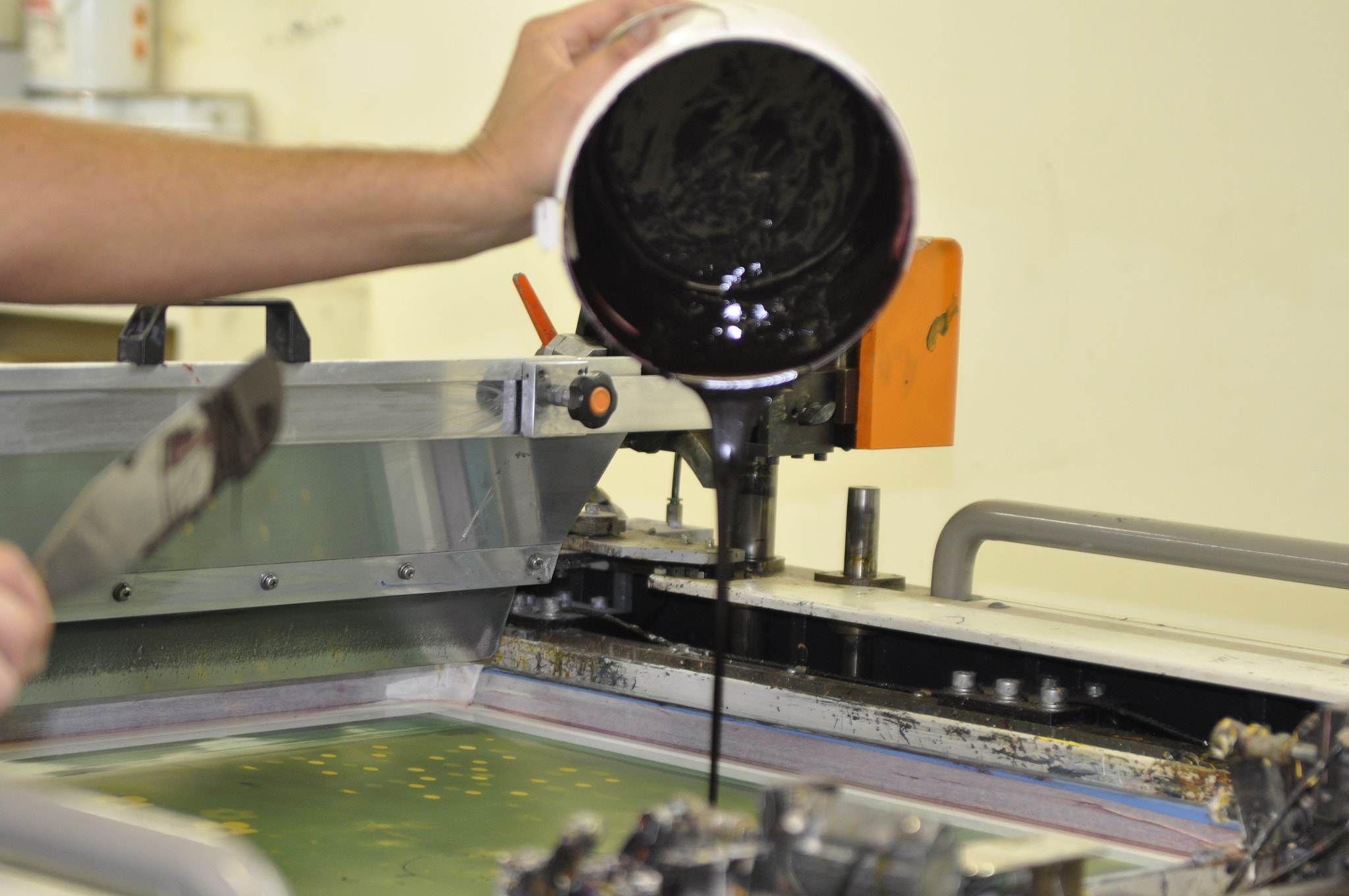 Nikon D90 sample photo. Screenprinter adding ink to a screen photography