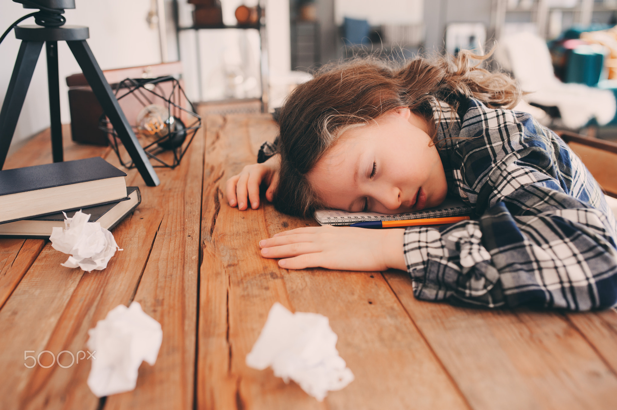 child girl sleeping while doing homework. School kid learning hard and get tired, papers with...