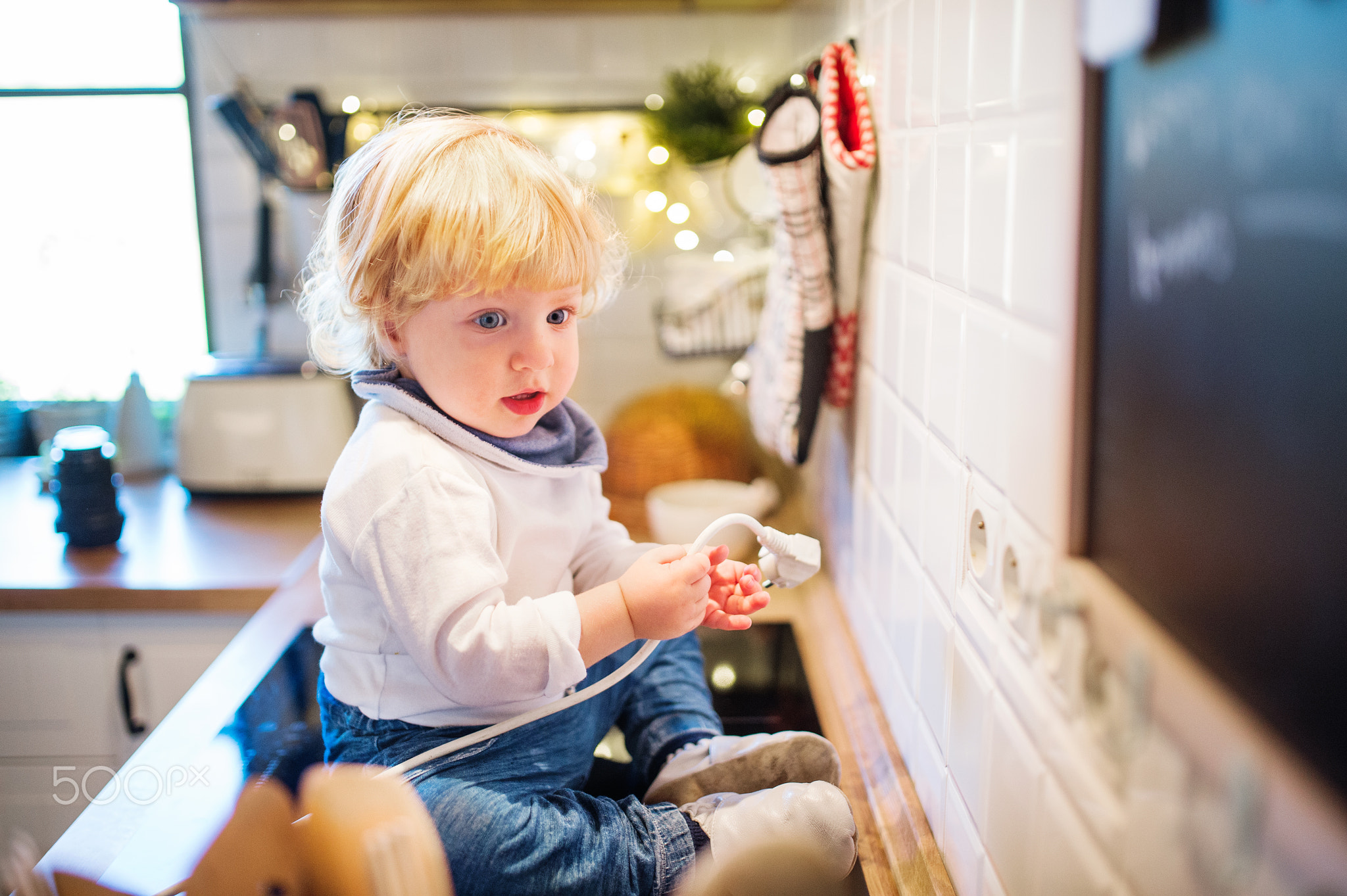 Toddler boy in dangerous situation at home. Child safety concept.