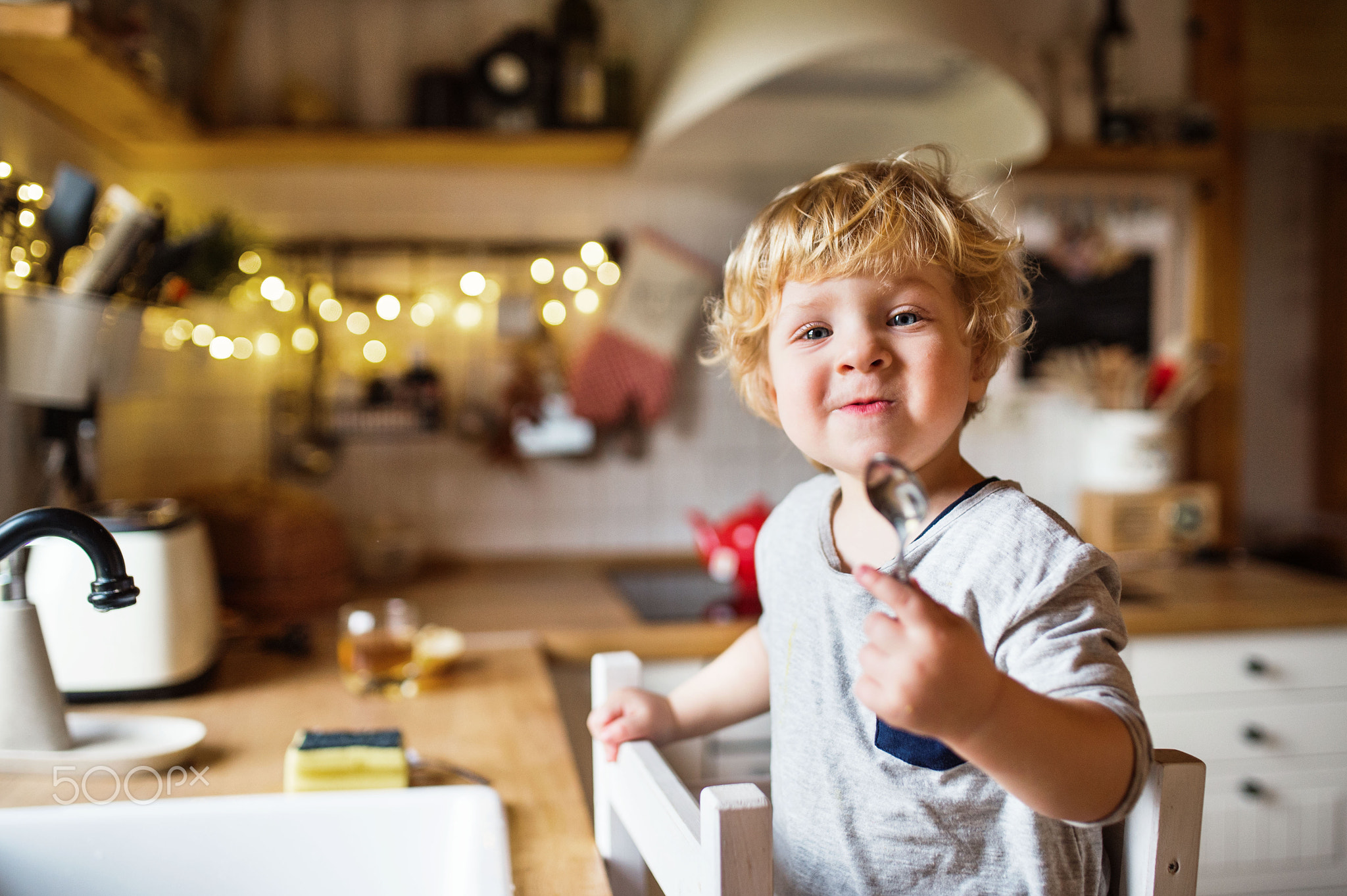 A toddler boy washing up the dishes.