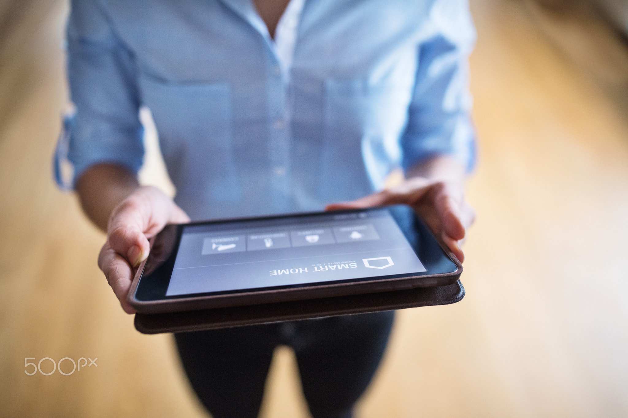 A woman holding a tablet with smart home screen.