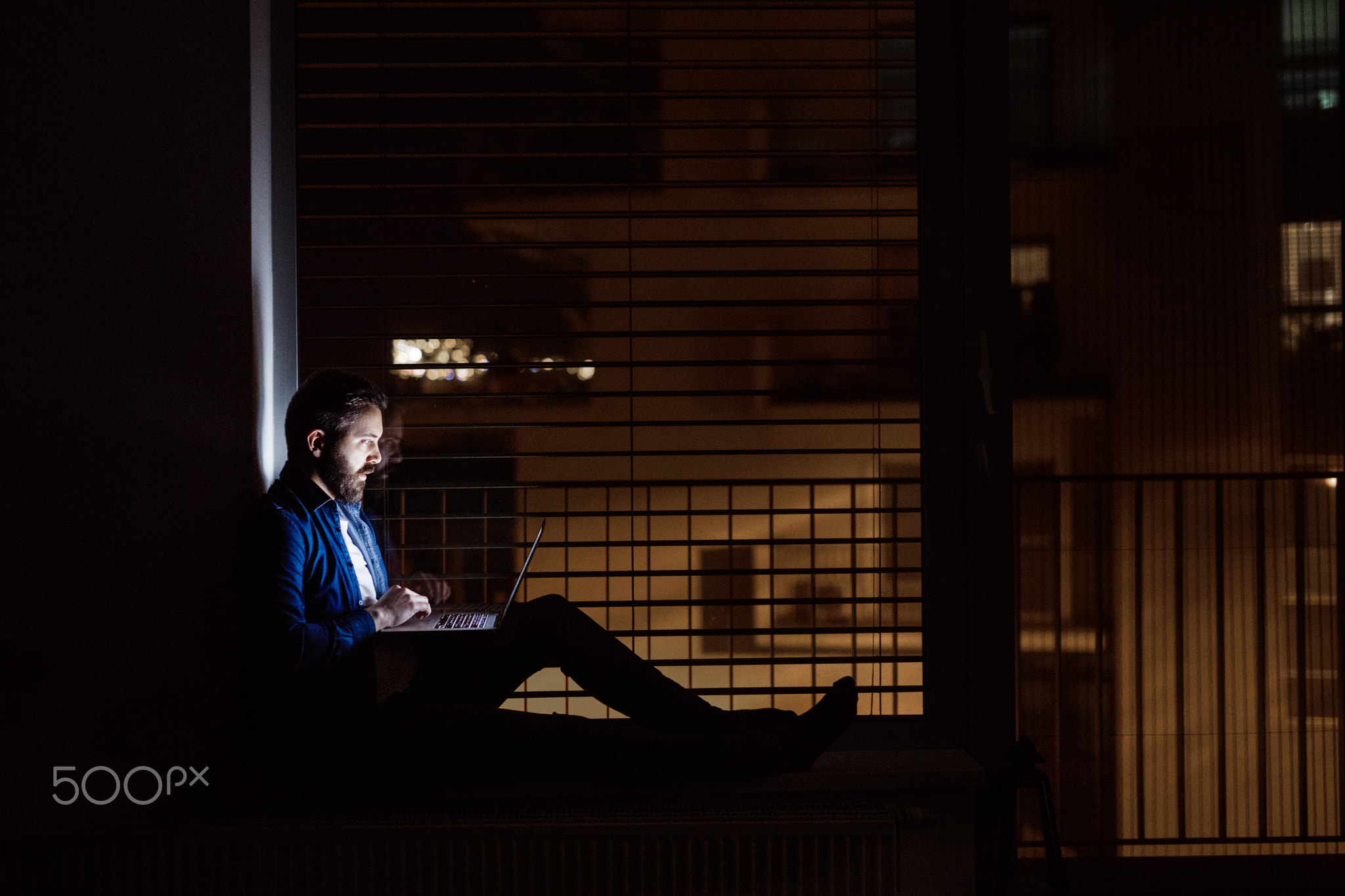 A man working on a laptop at home at night.