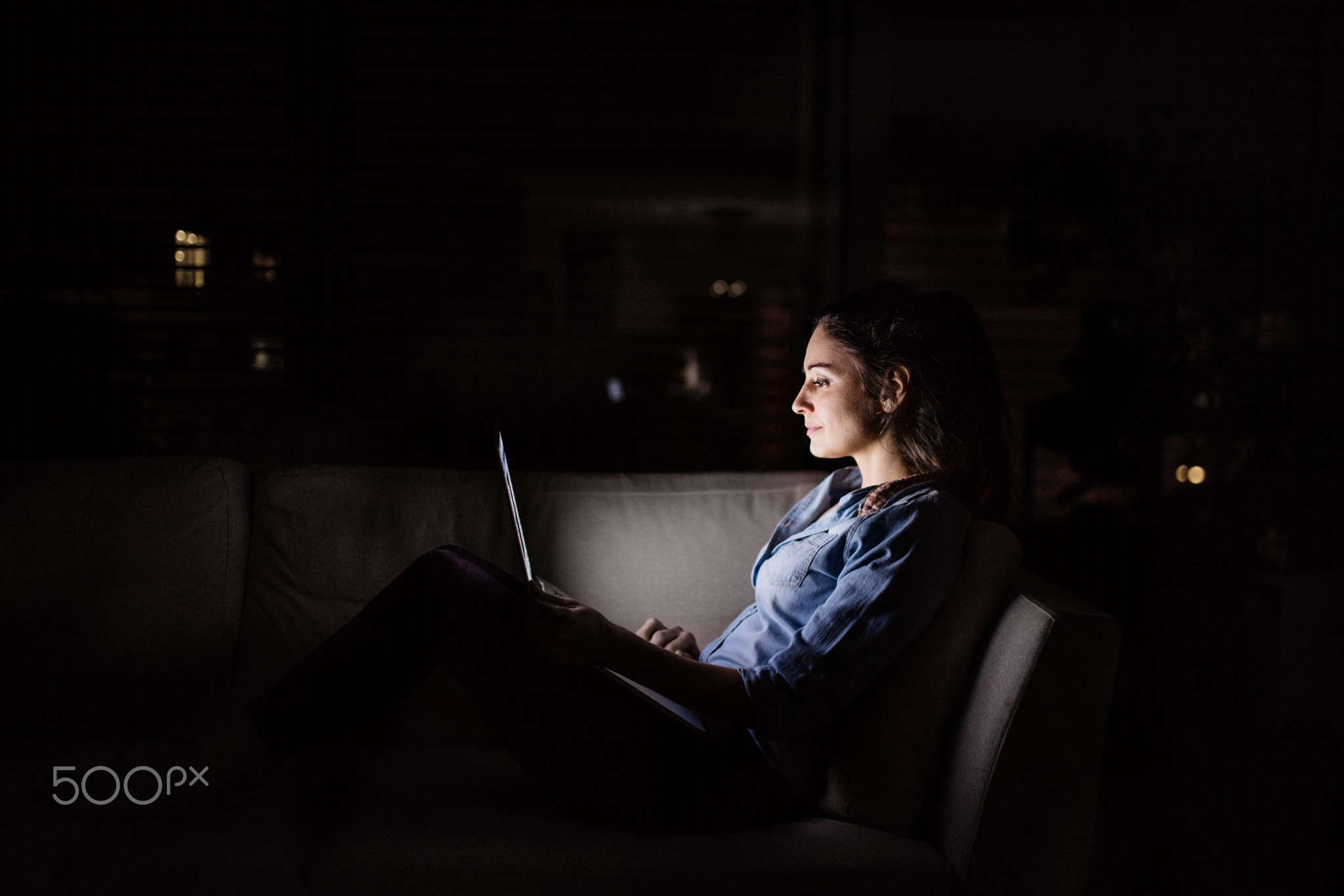 A woman working on a laptop at night at home.