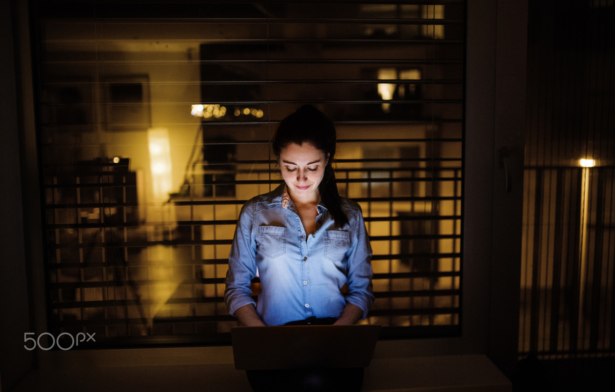 A woman working on a laptop at home or in the office at night.