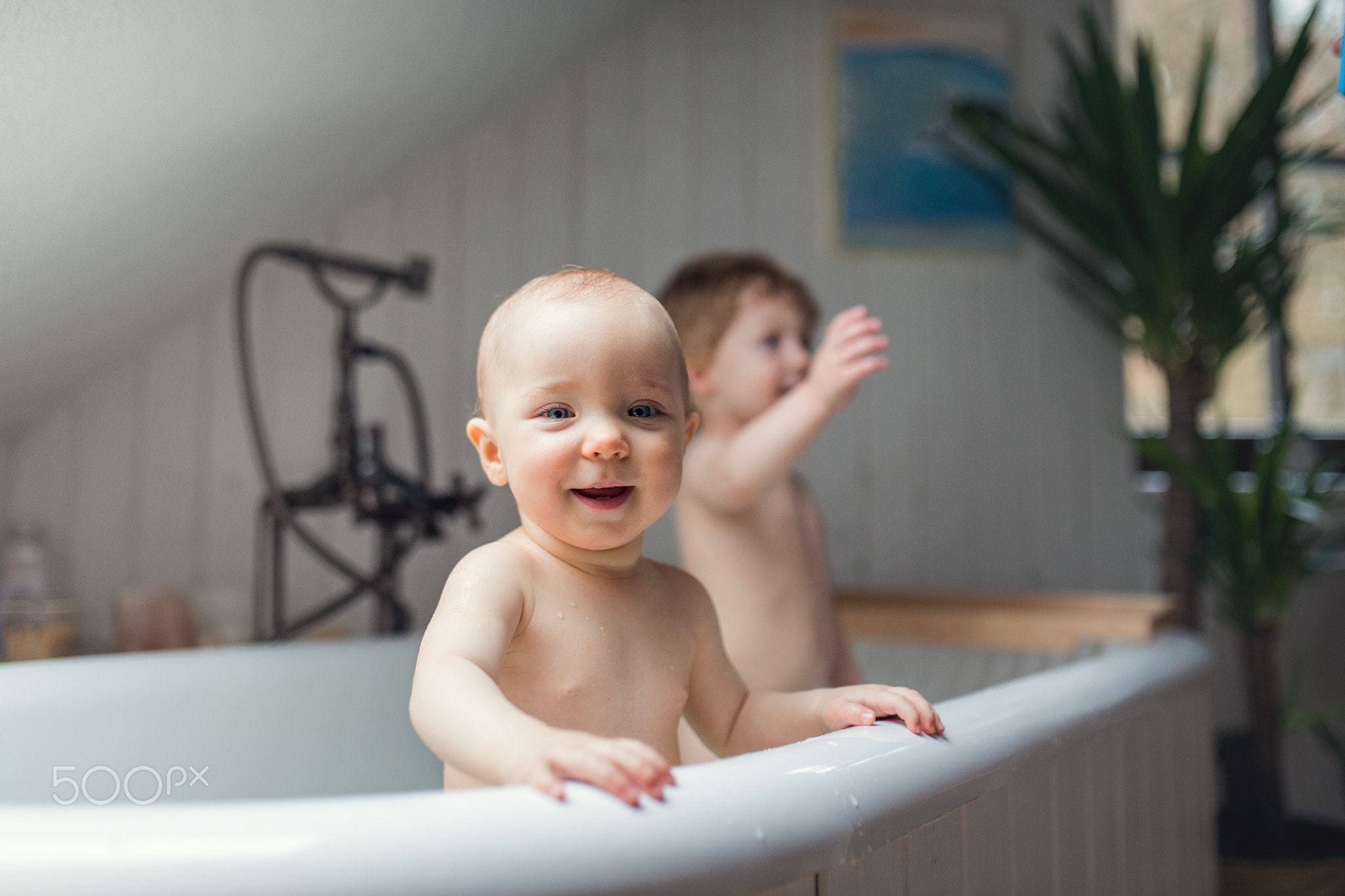 Two toddler children having a bath in the bathroom at home.