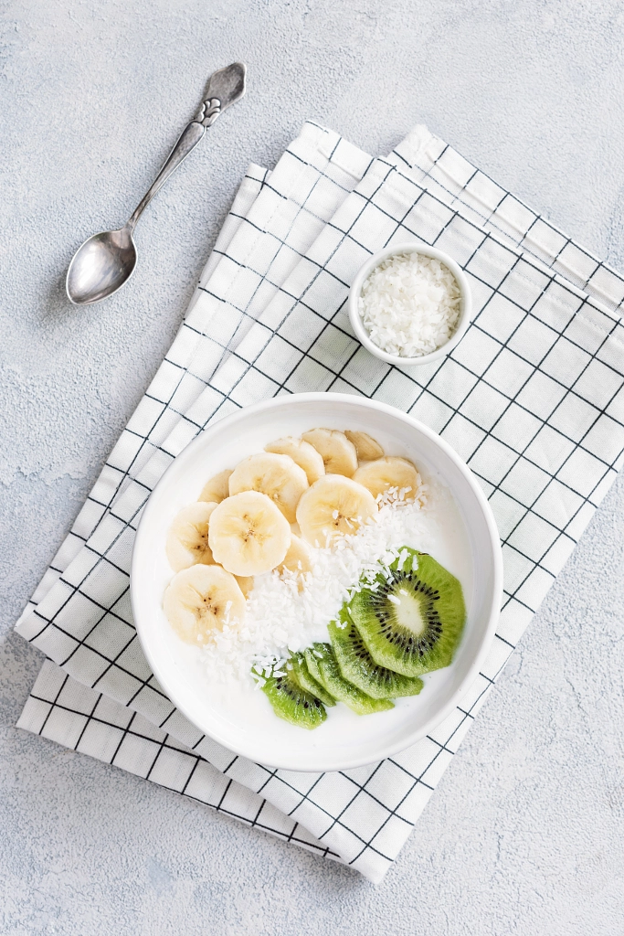 Paleo yogurt bowl with banana, kiwi and coconut flakes by Vladislav Nosick on 500px.com