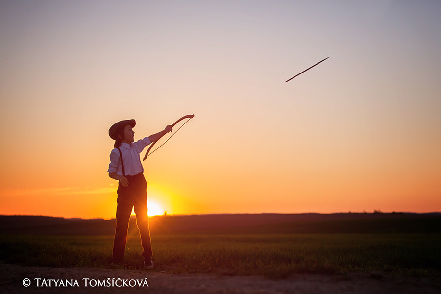 Silhouette of child playing with bow and arrows, archery shoots