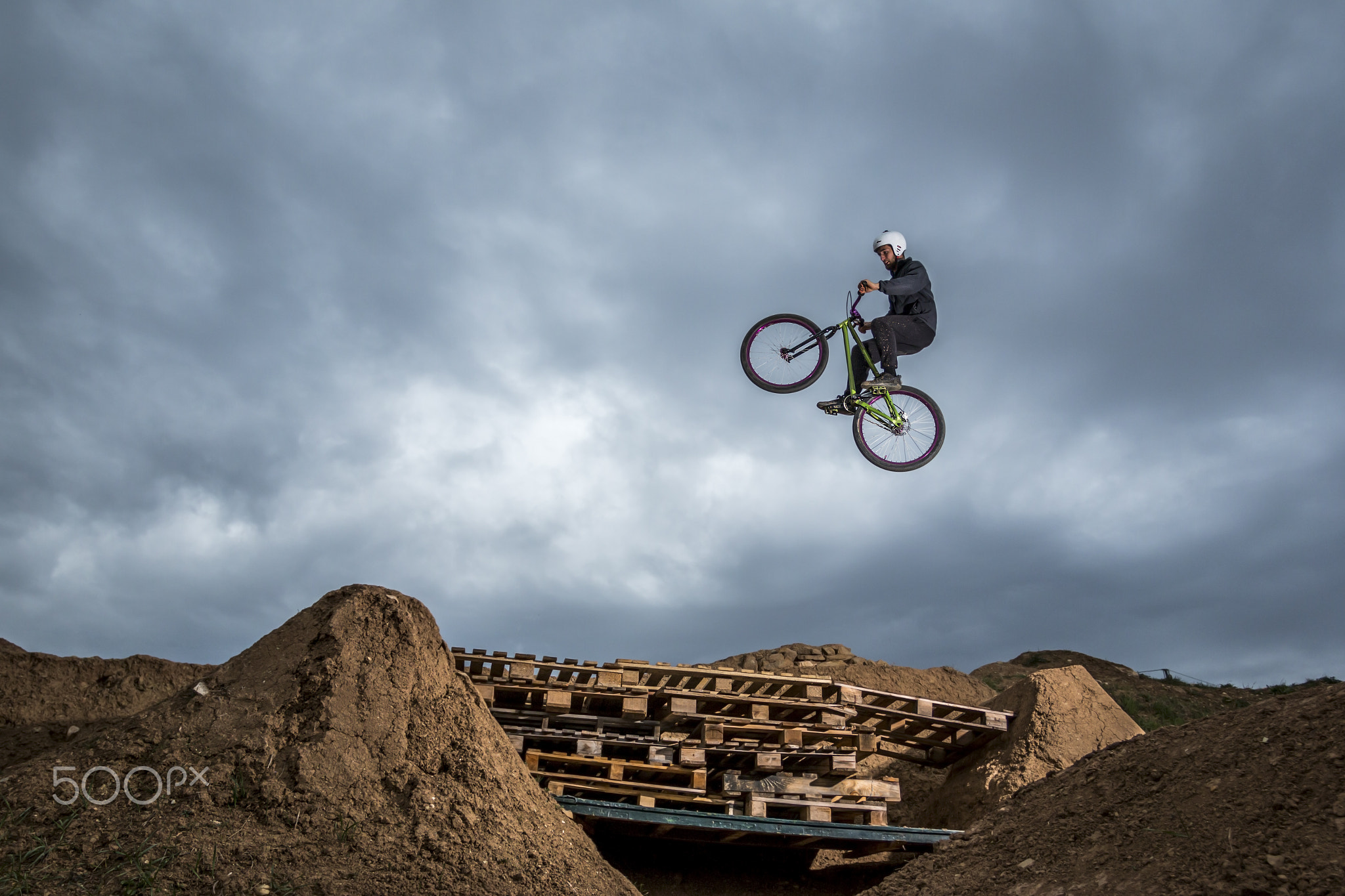 Young man jumping over hole in dirtjump circuit