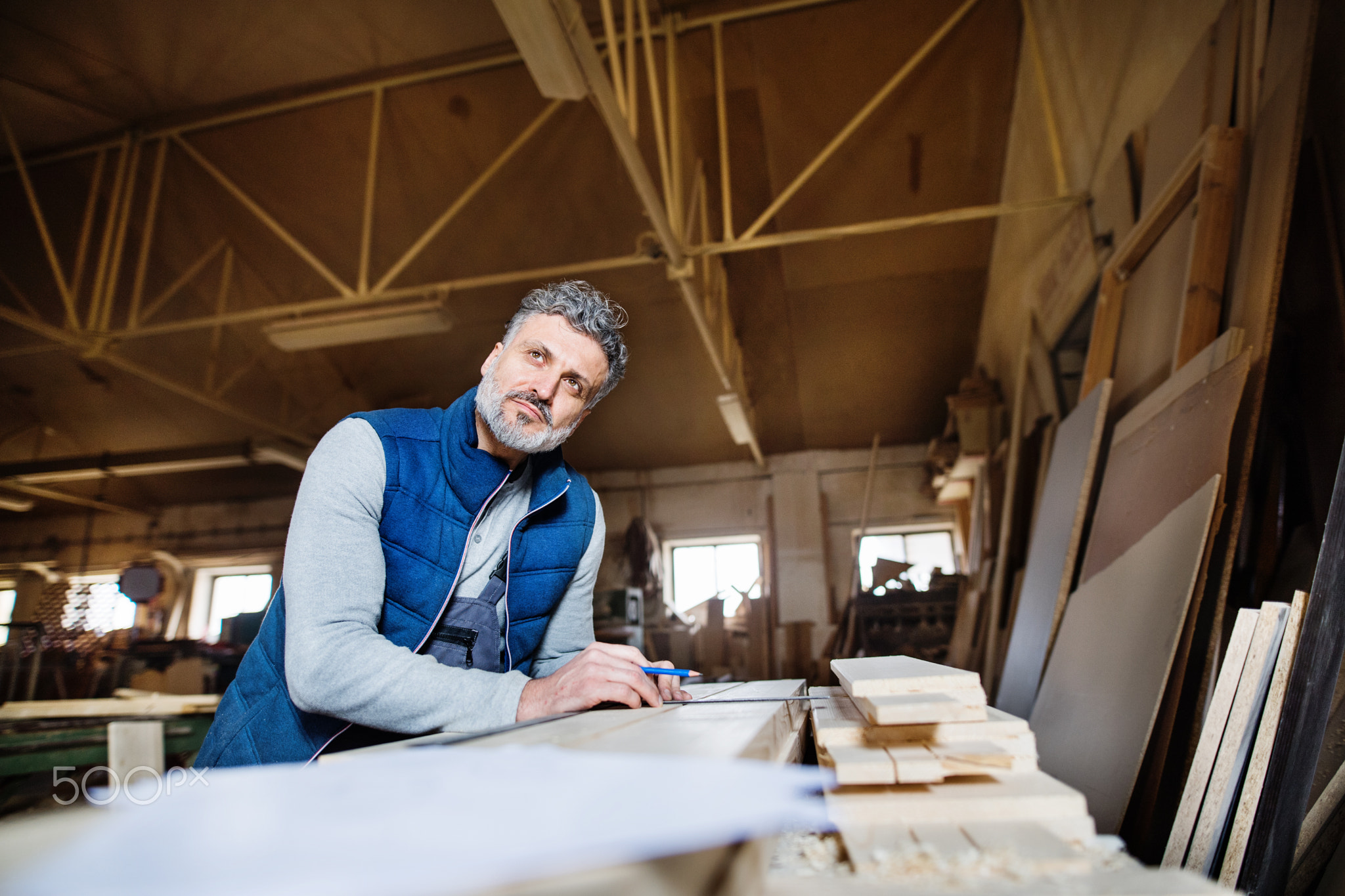 A man worker in the carpentry workshop, working with wood.