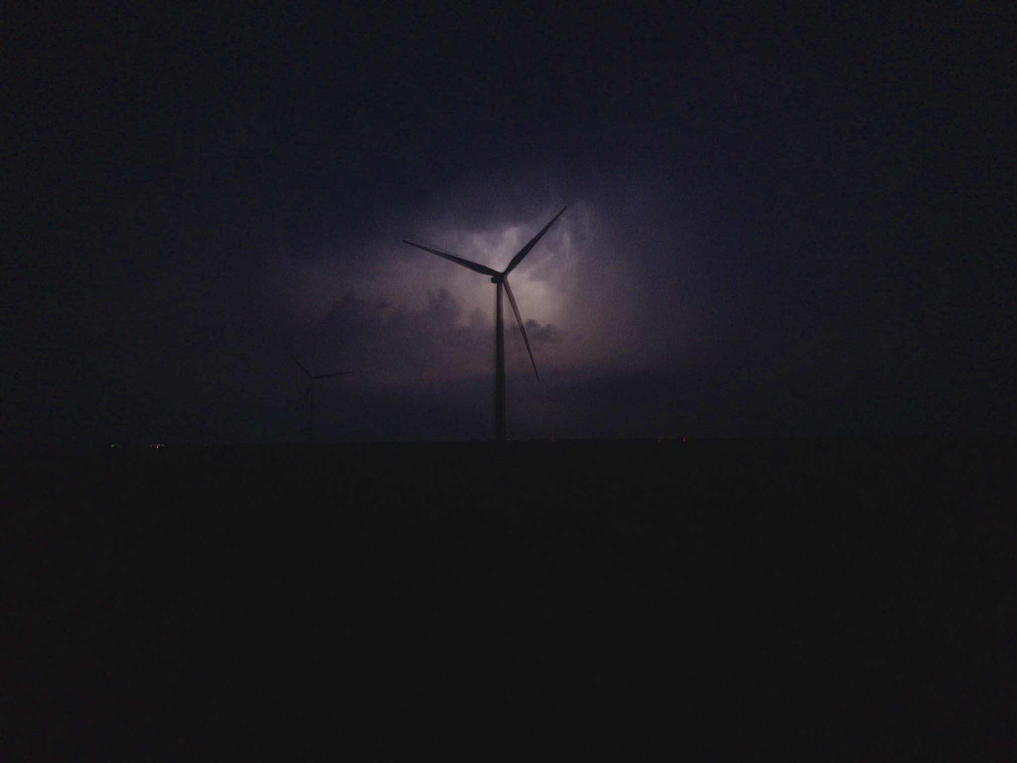 Apple iPhone sample photo. Distant lightning backlight a windmill on the southern plains at night photography