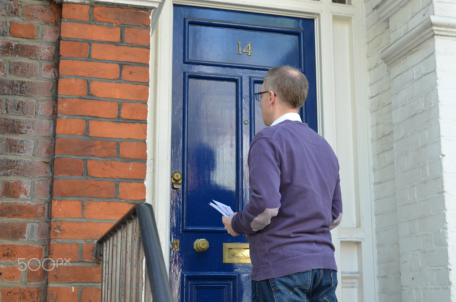 Nikon D7000 + Nikon AF-S DX Nikkor 35mm F1.8G sample photo. Male canvasser knocking on a blue door photography