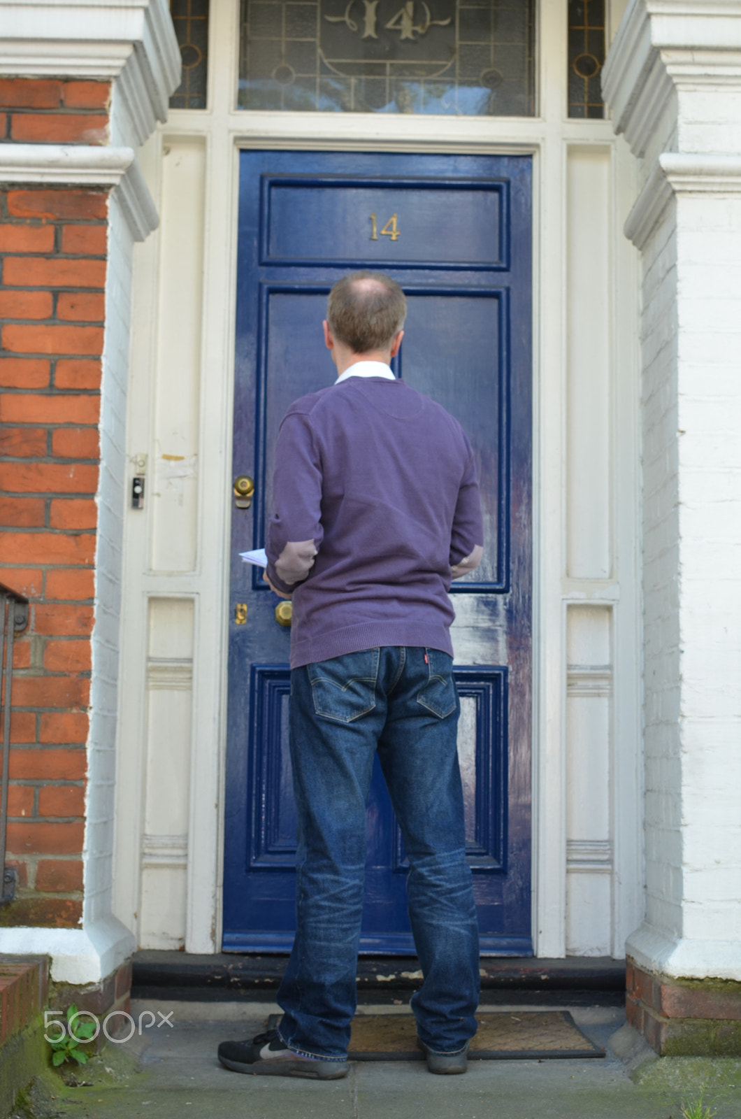 Nikon D7000 + Nikon AF-S DX Nikkor 35mm F1.8G sample photo. Male canvasser knocking on a blue door photography