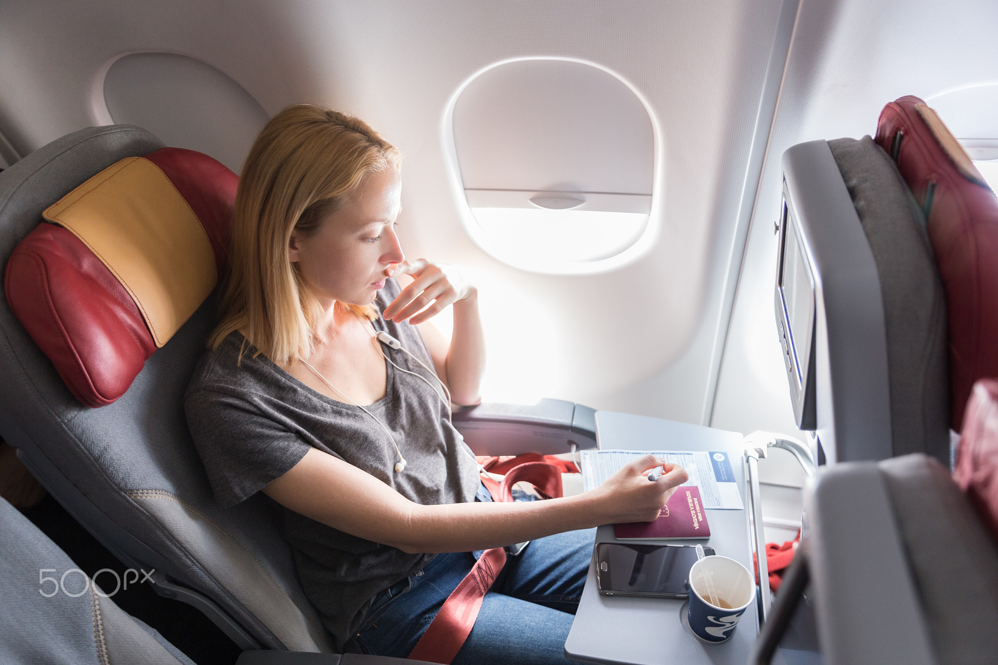 Woman filling immigration form on commercial passengers airplane during flight.