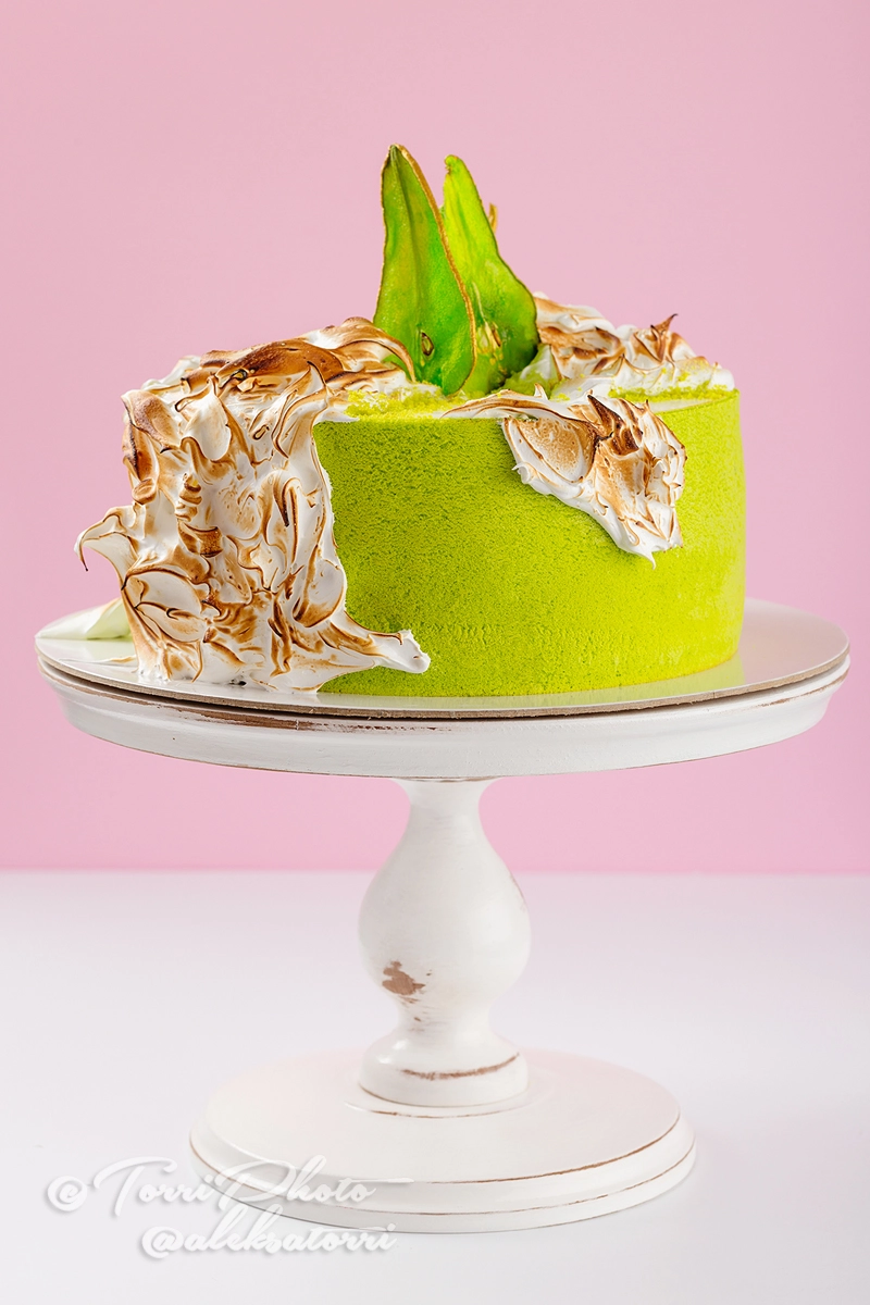 Green cake decorated with burned meringue and colored pear