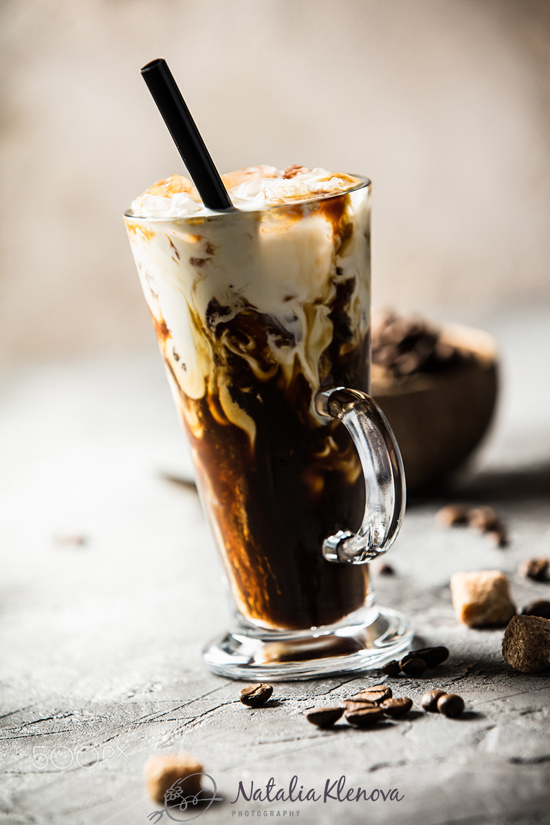 Iced coffee in a tall glass with cream poured over