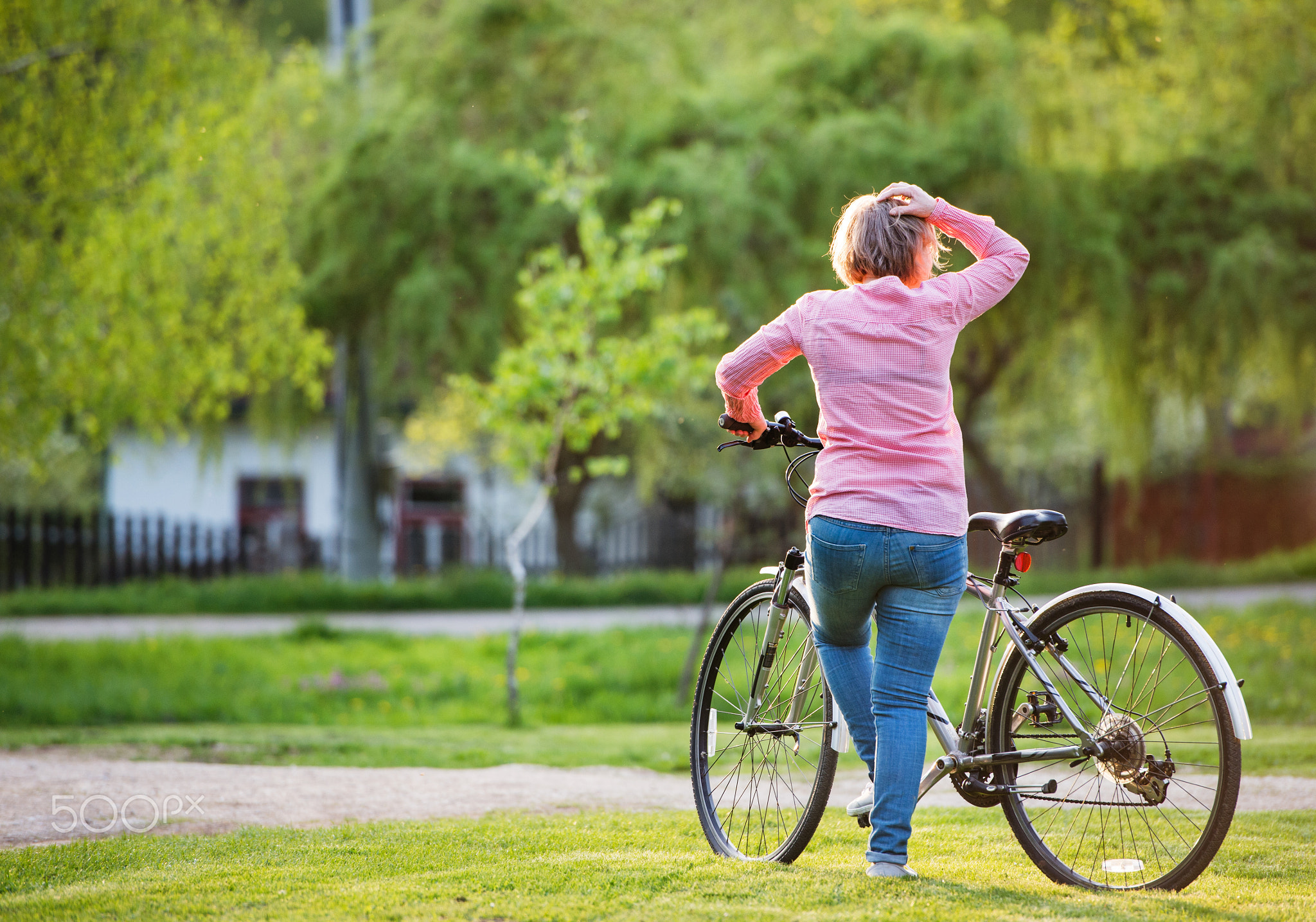 Senior woman with bicycle outside in spring nature.