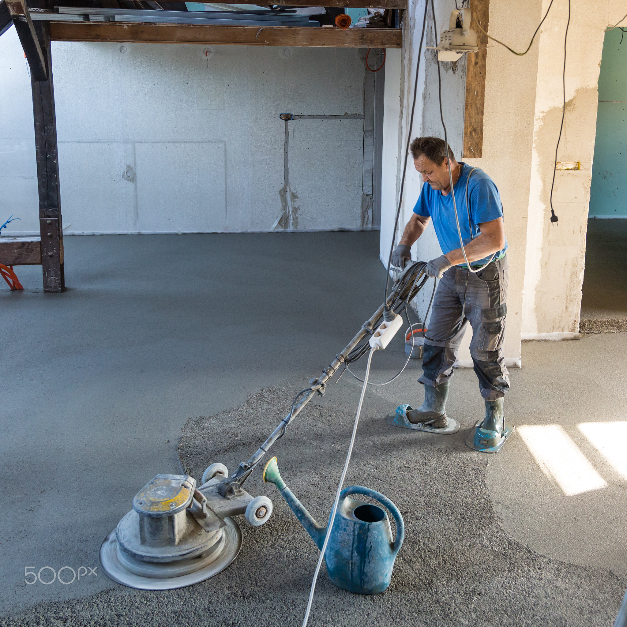 Laborer polishing sand and cement screed floor.