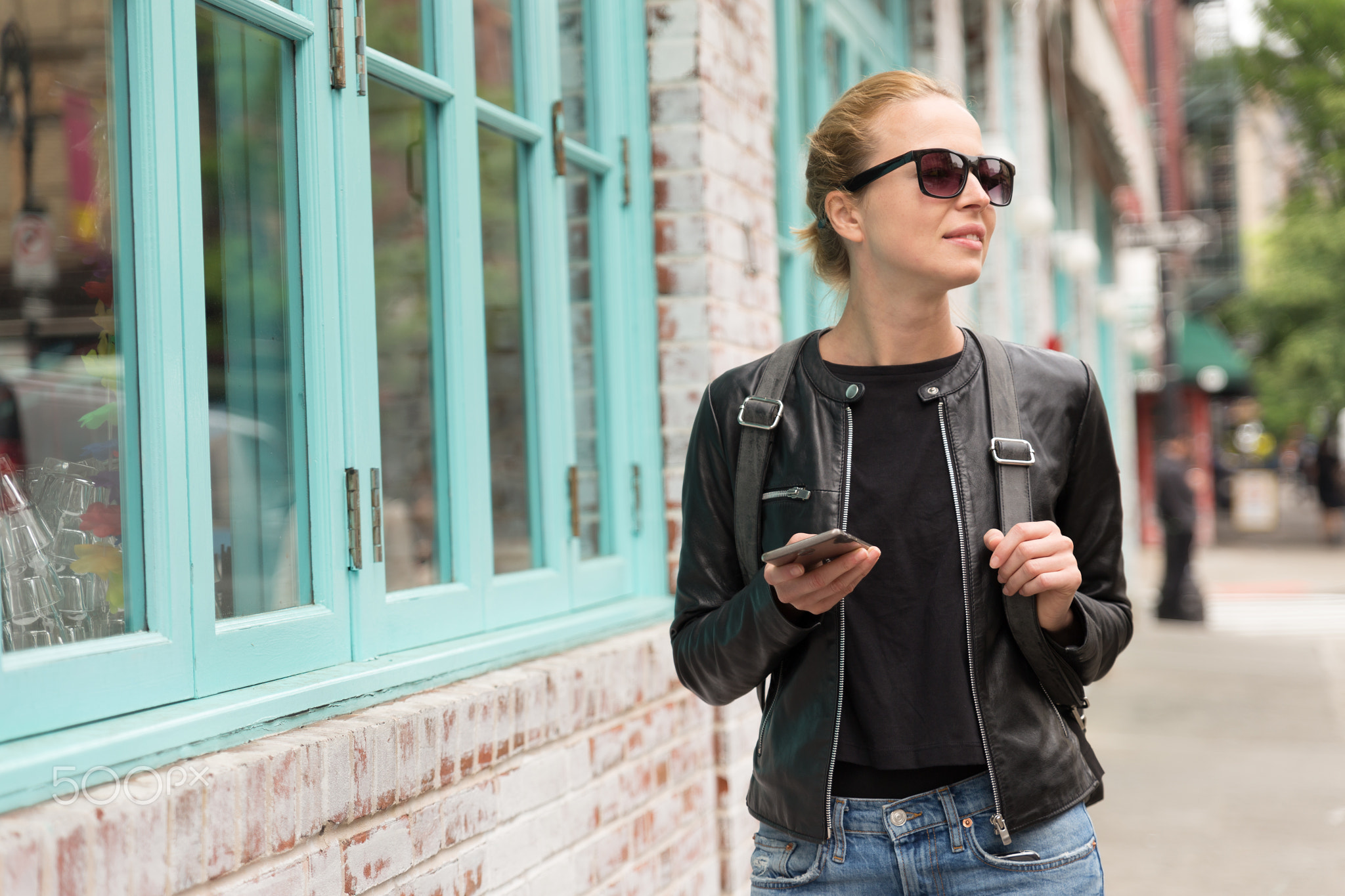 Female traveler using smart phone app guite on city break weekend trip to New York.