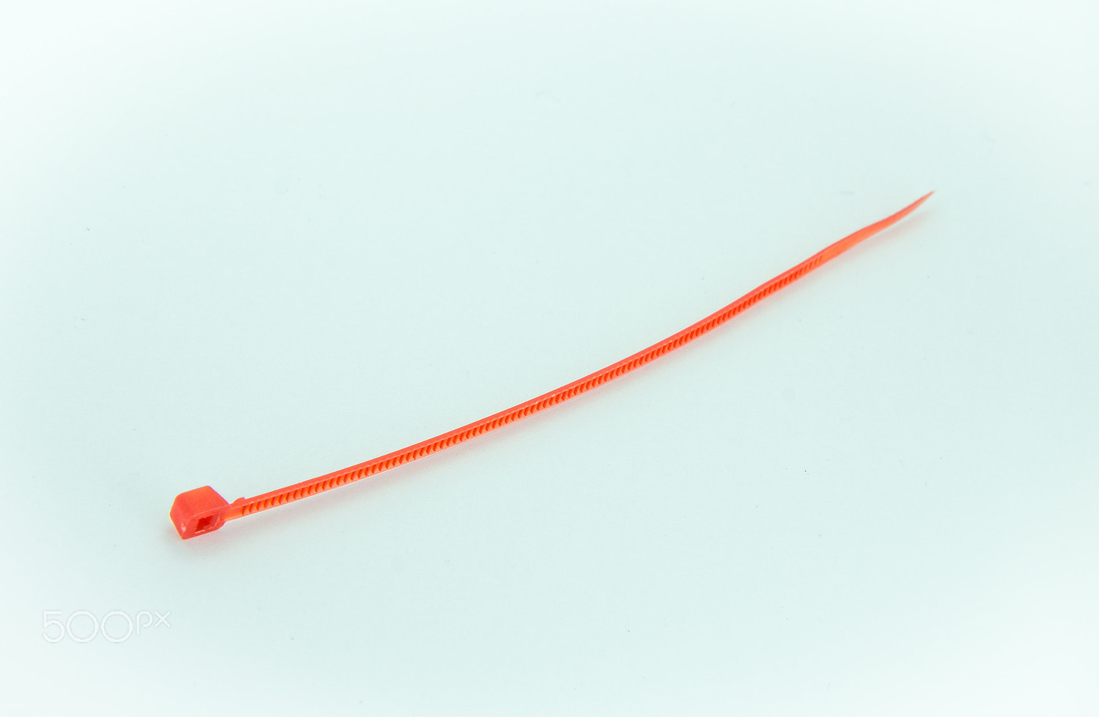 Canon EOS M sample photo. A red nylon cable ties on white background photography