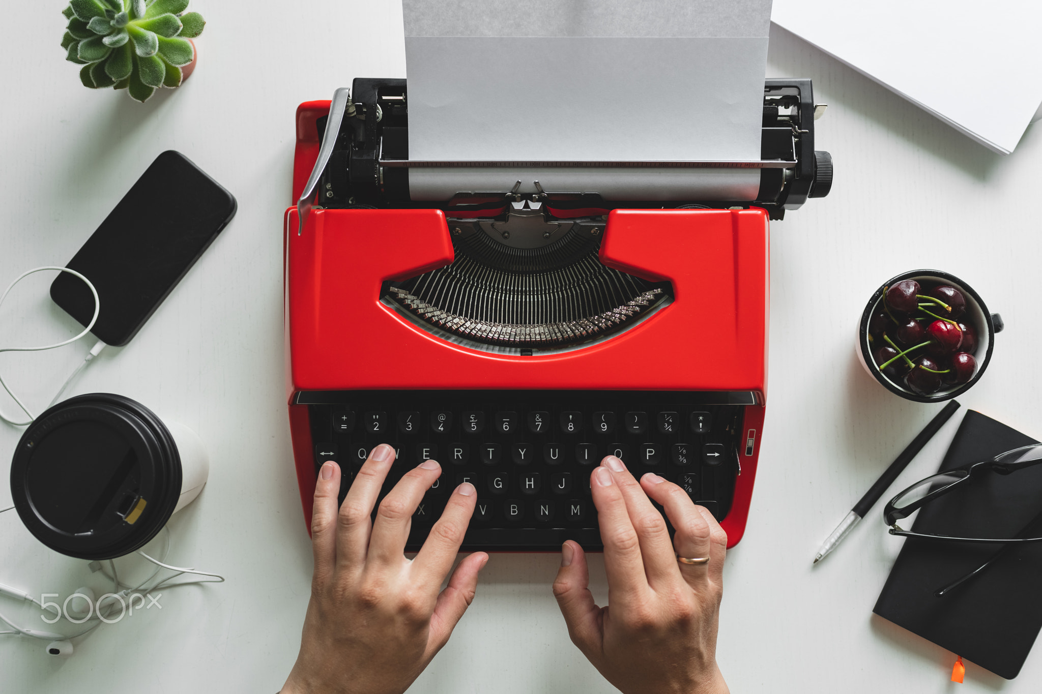 Woman hand working with bright red vintage typewriter