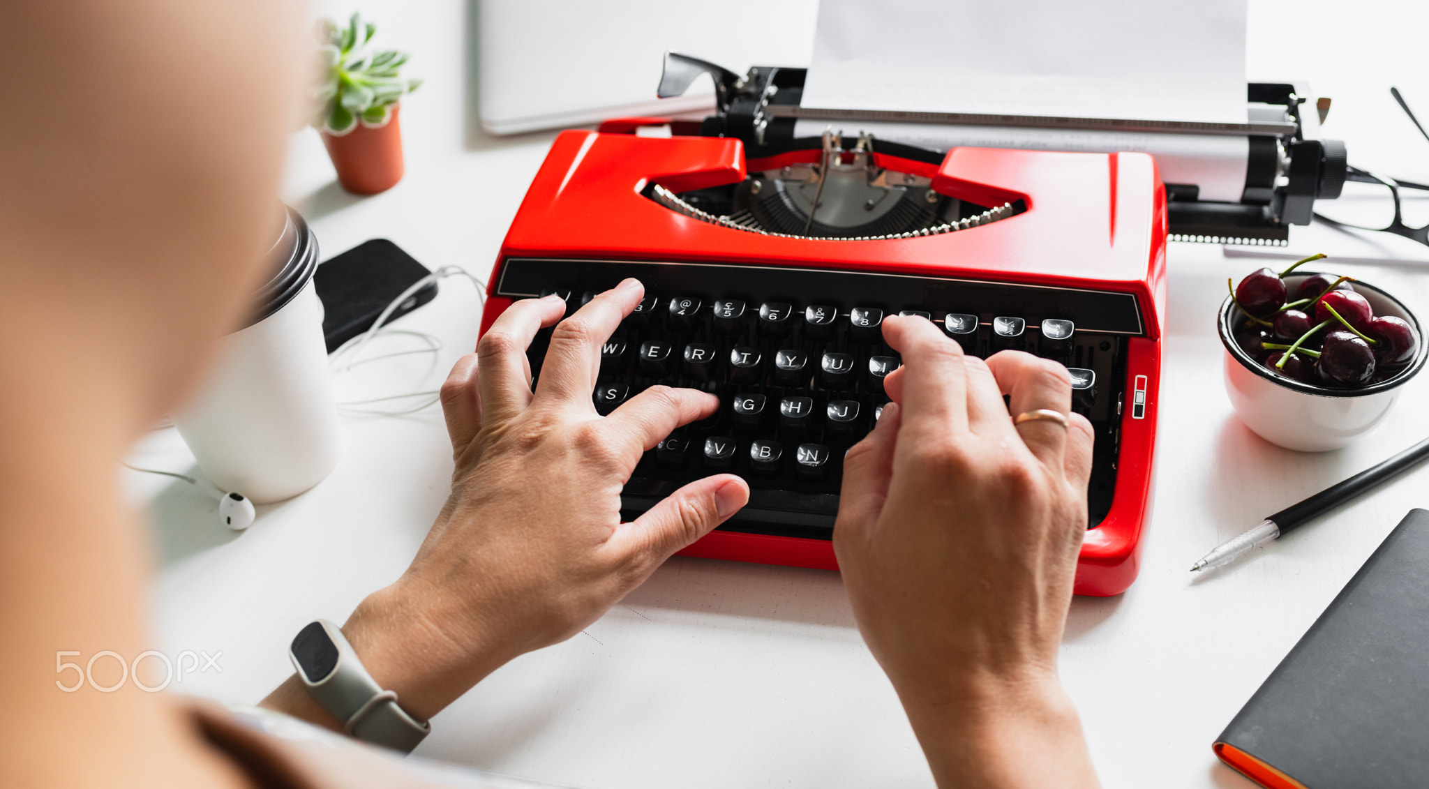 Woman hand working with bright red vintage typewriter