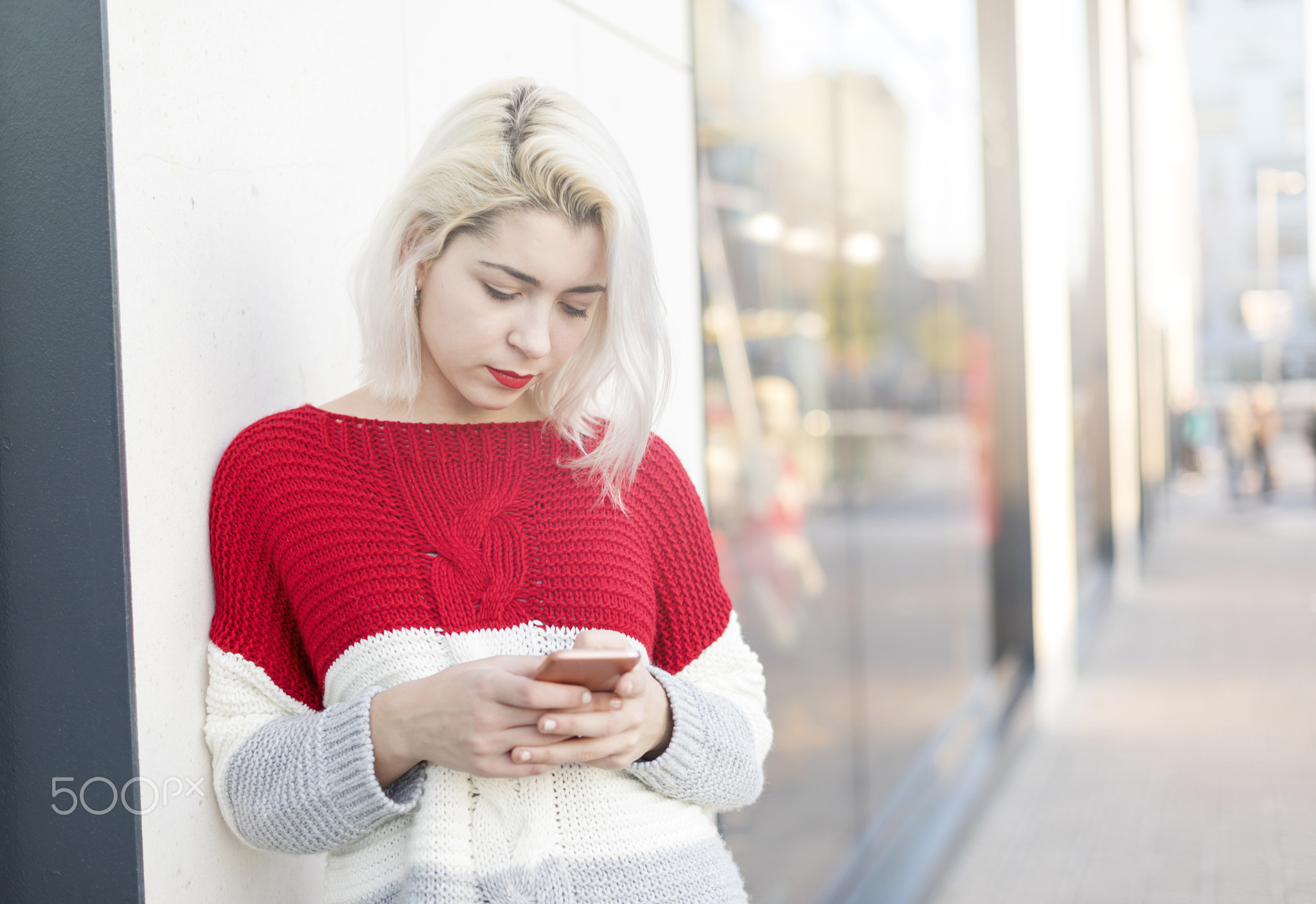 Beautiful woman writing a message on her phone while doing shopp