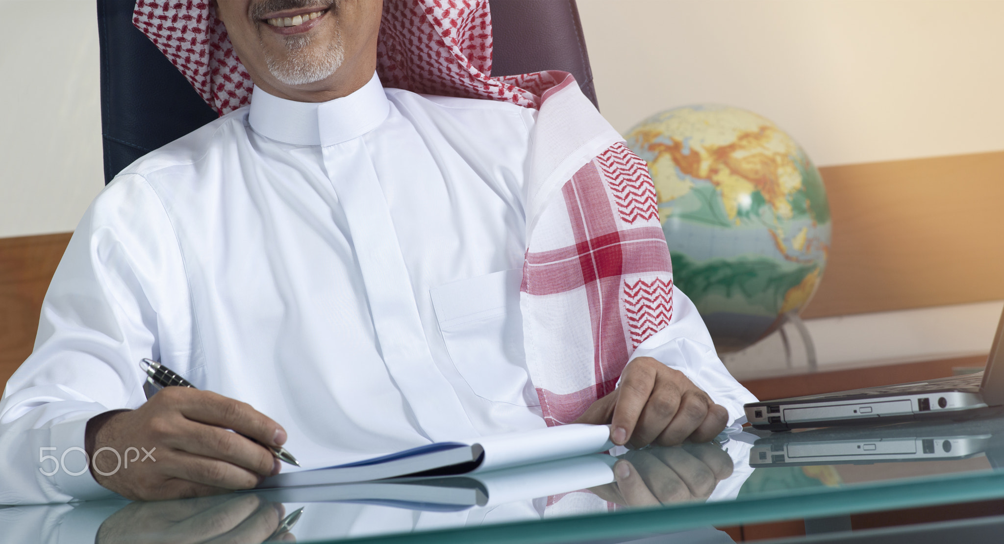 Senior Saudi Businessman Hand Writing At His Desk