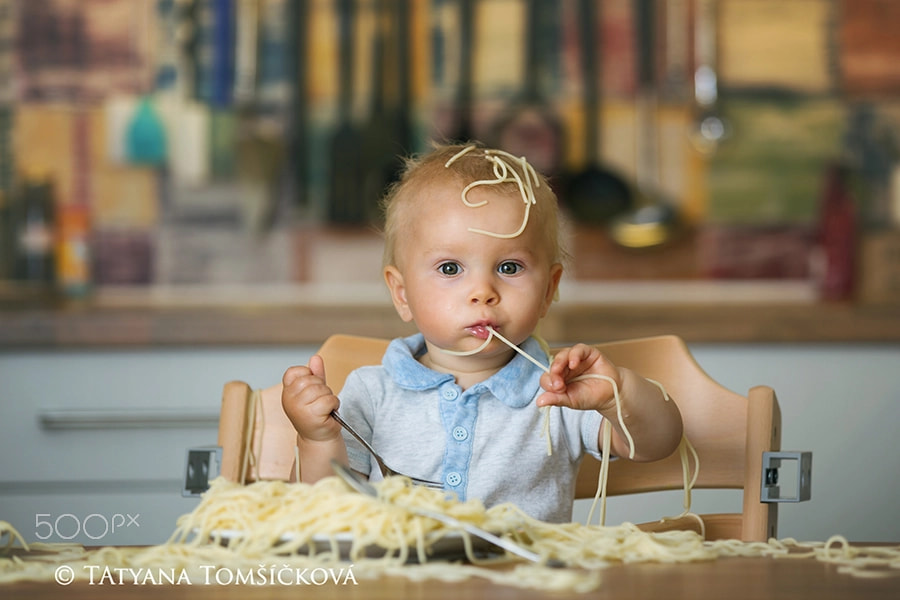 Little baby boy, toddler child, eating spaghetti for lunch and m