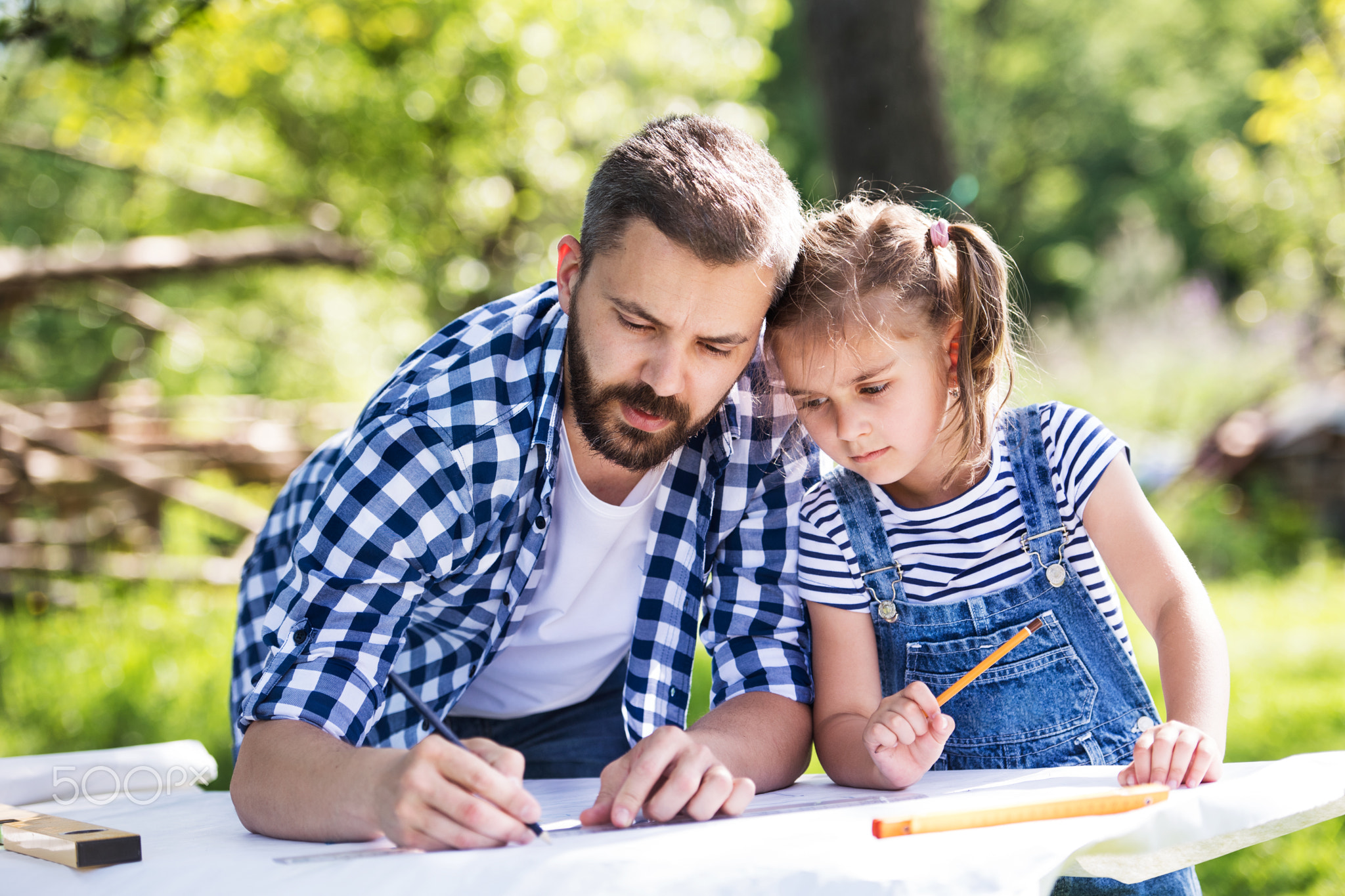 Father with a small daughter outside, planning wooden birdhouse.