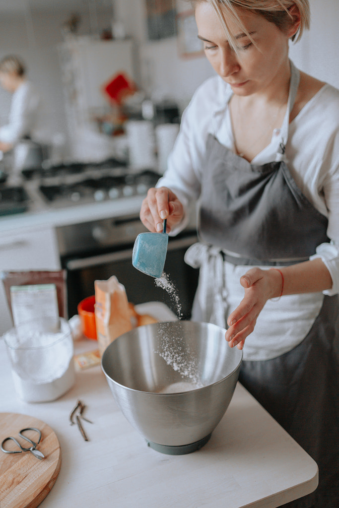 Young female pastry chef or a baker preparing a cake. by Irina Polonina on 500px.com