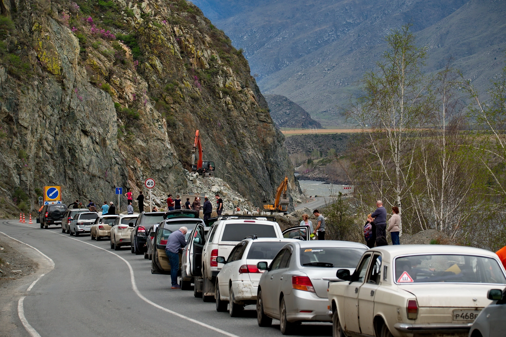 Russia. Mountain Altai. The queue of tourists on cars is waiting for the removal of heavy road...