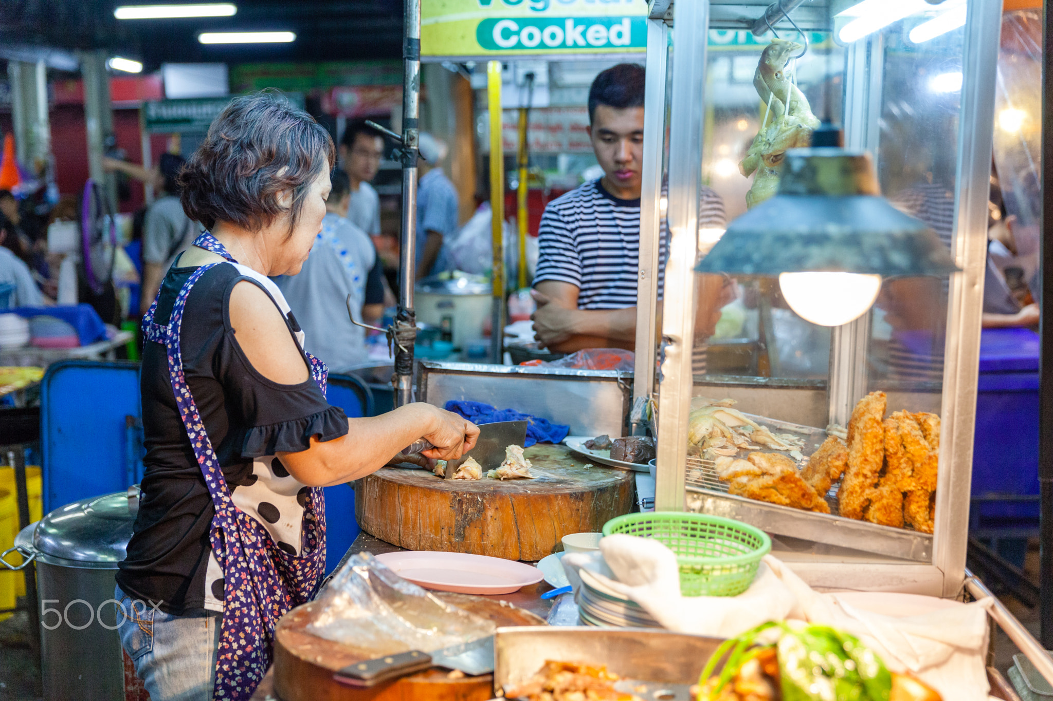 A senior woman prepares chiken for sale