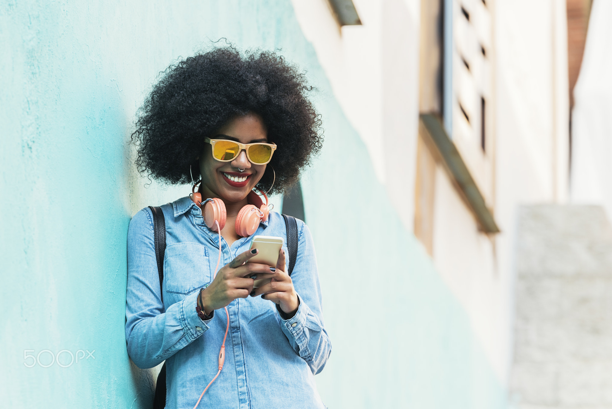 Beautiful afro american woman using mobile in the street.