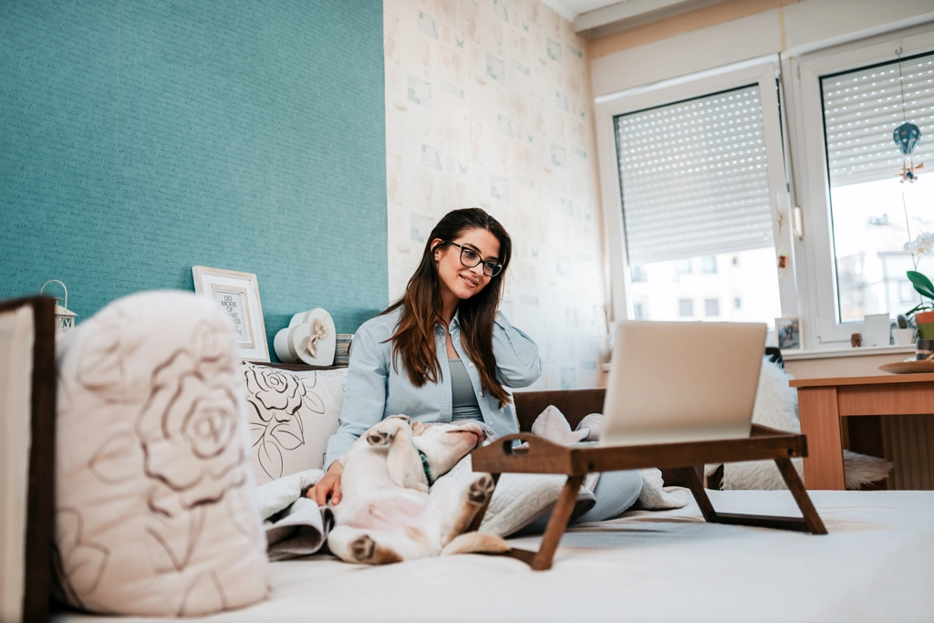 Cheerful woman using laptop while sitting on sofa with dog. by Branislav Nenin on 500px.com