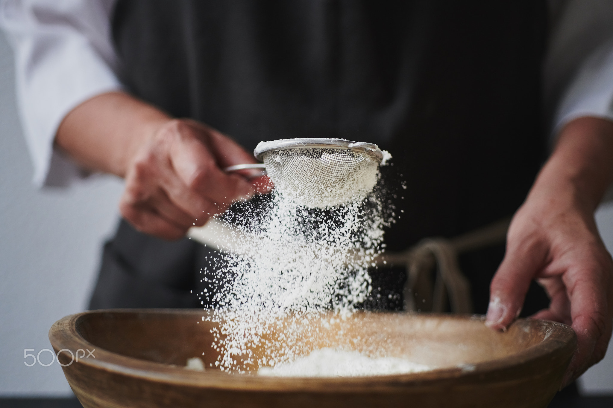 Female hands sifting flour to bowl.