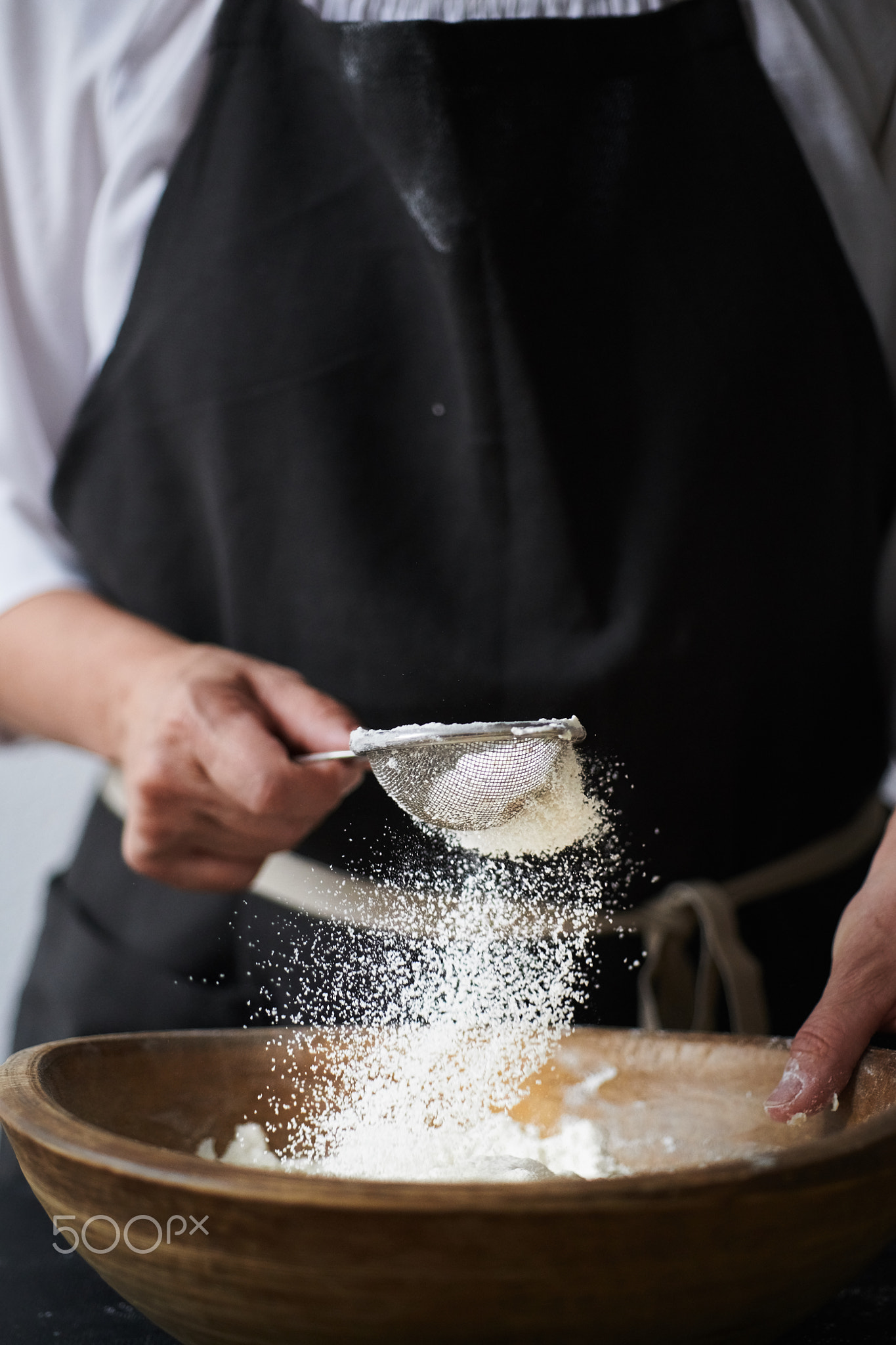 Female hands sifting flour to bowl.