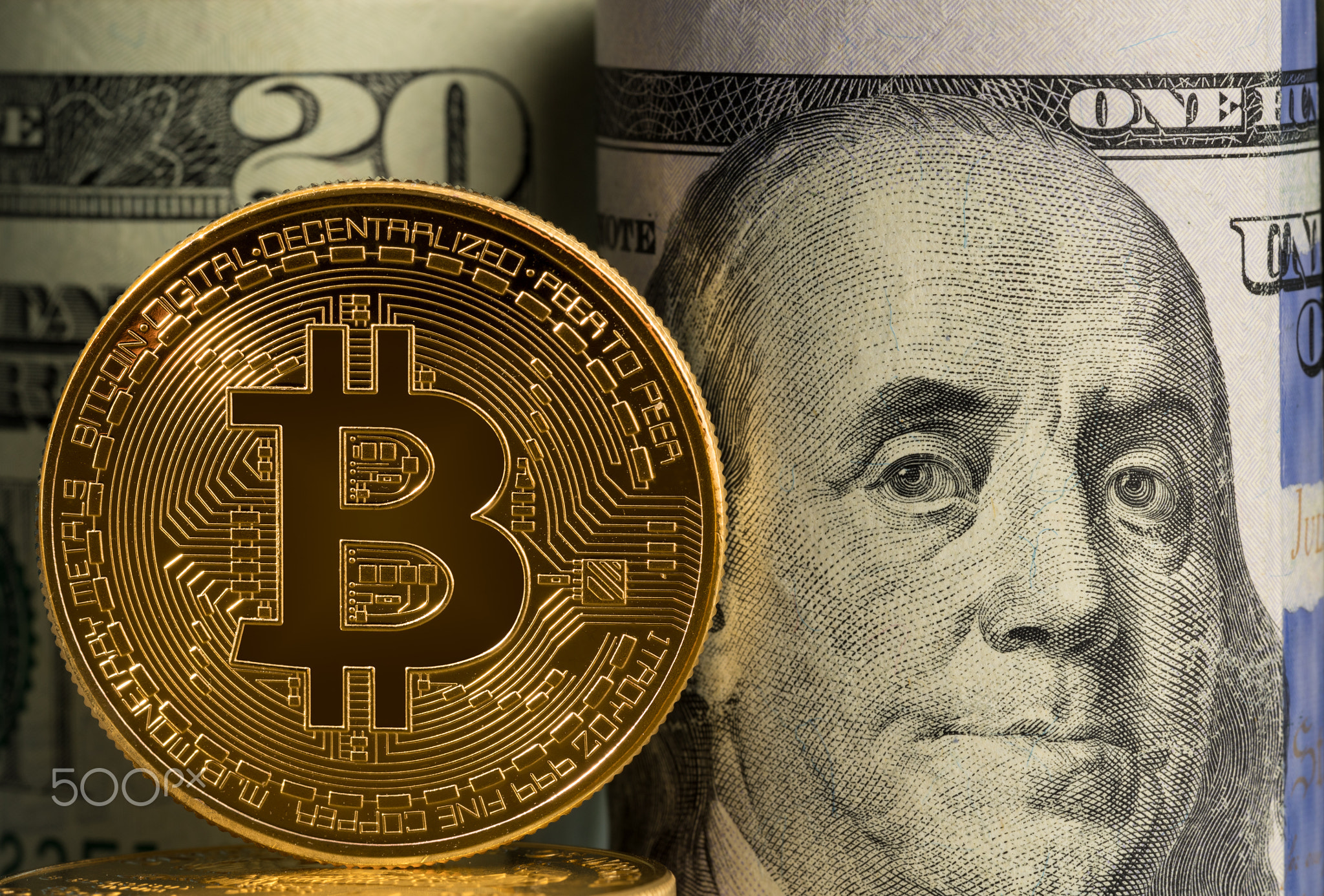 Bitcoin coin in front of bank rolls of US currency