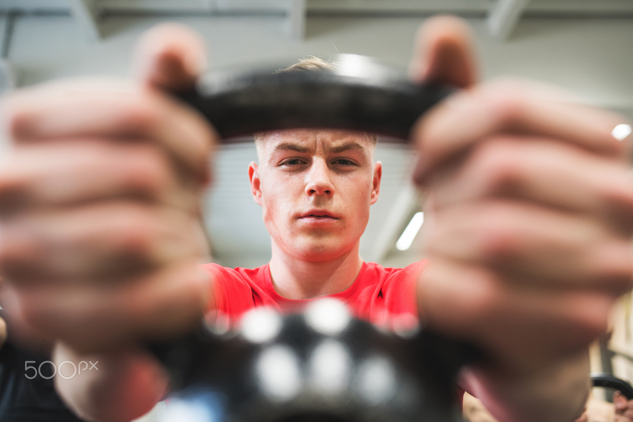 Young fit man in gym lifting kettlebell. Close-up.