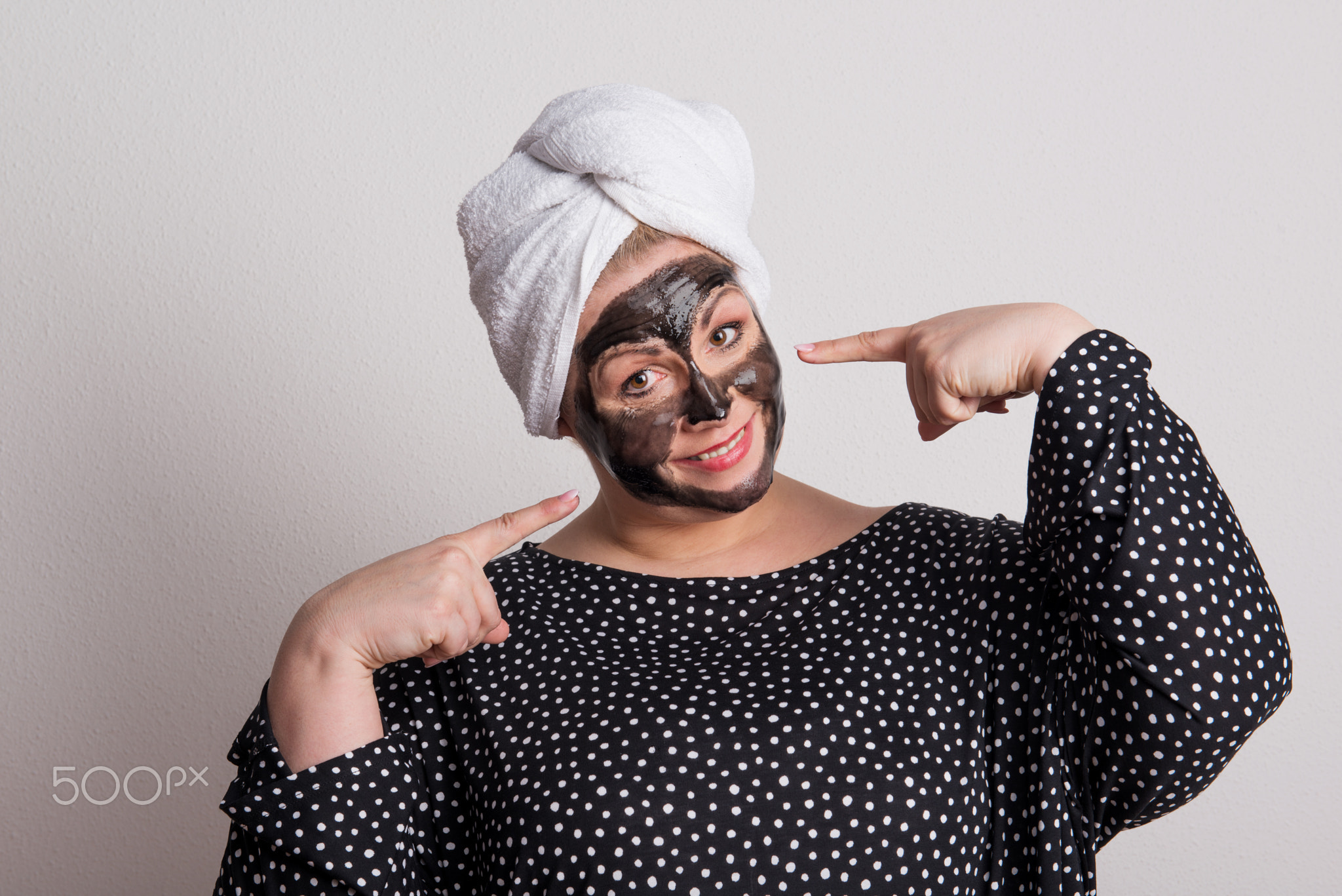An attractive overweight woman with black facial mask on her face in a studio.
