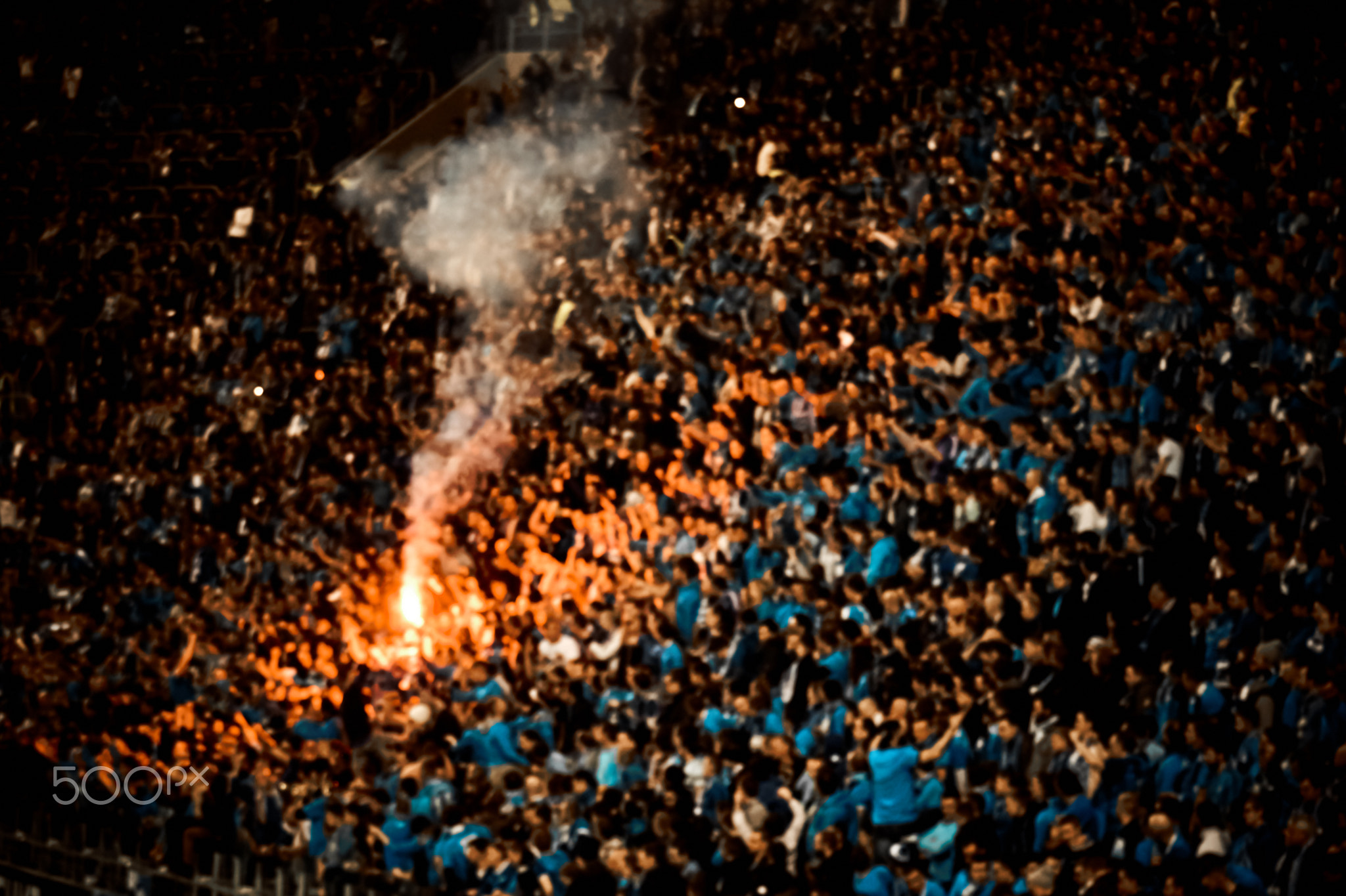 Football fans cheer their soccer team score goal with the fire at the stadium