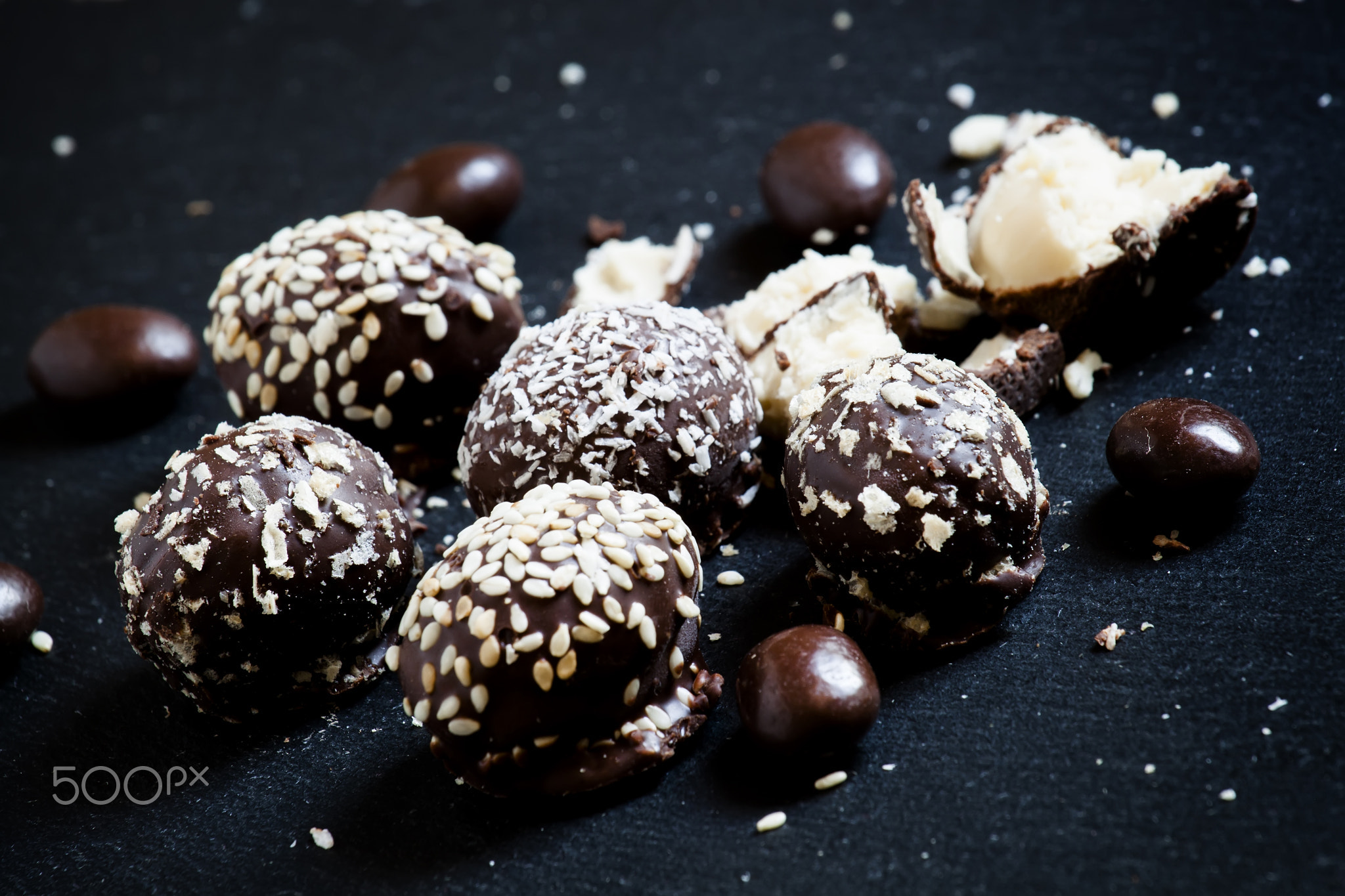 Chocolate candies with stuffing on a dark stone background, sele